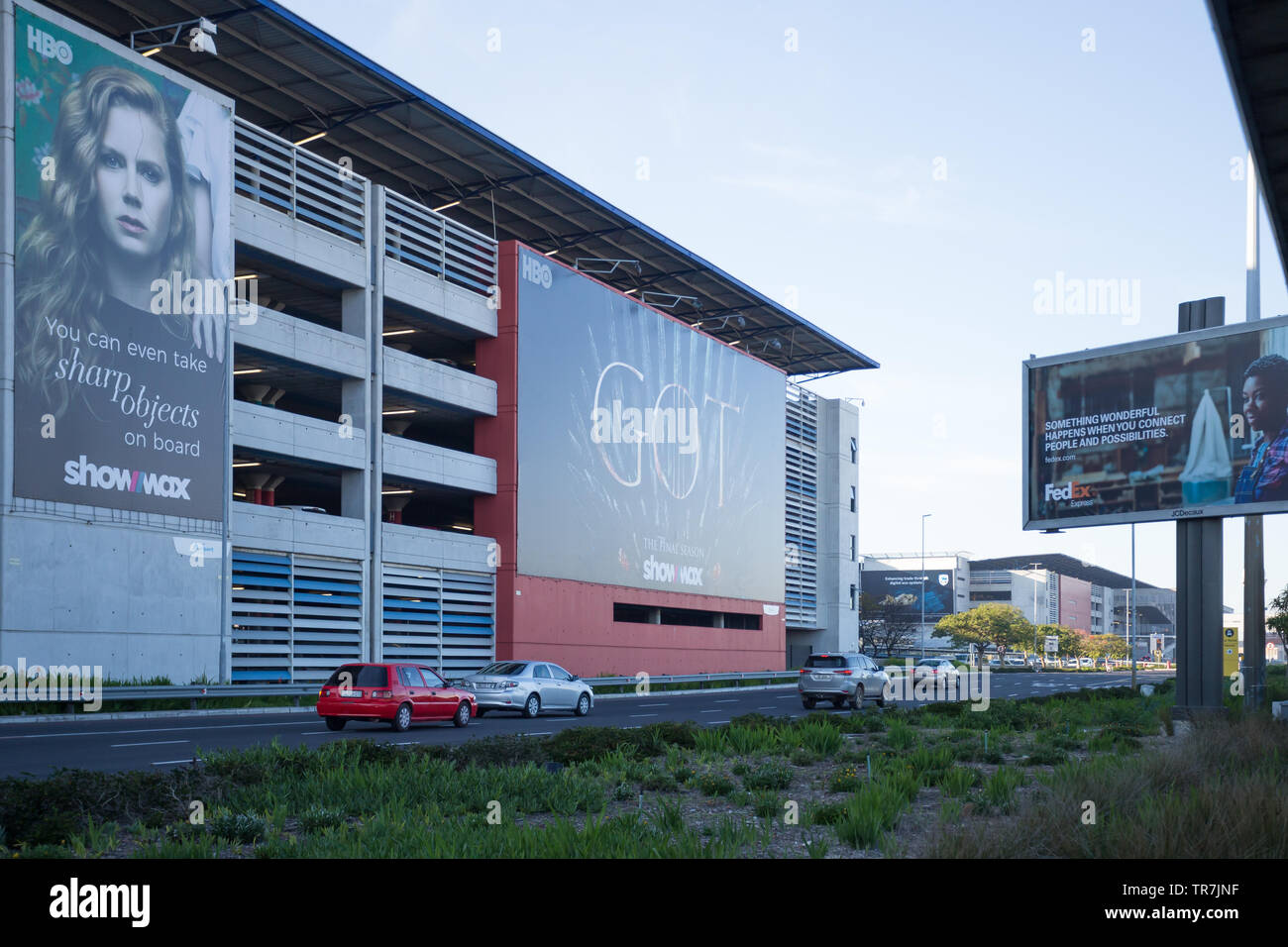 Strada pubblica con vetture passando per il parcheggio auto edificio e dirigendosi verso il terminal all'Aeroporto Internazionale di Città del Capo in Sud Africa Foto Stock