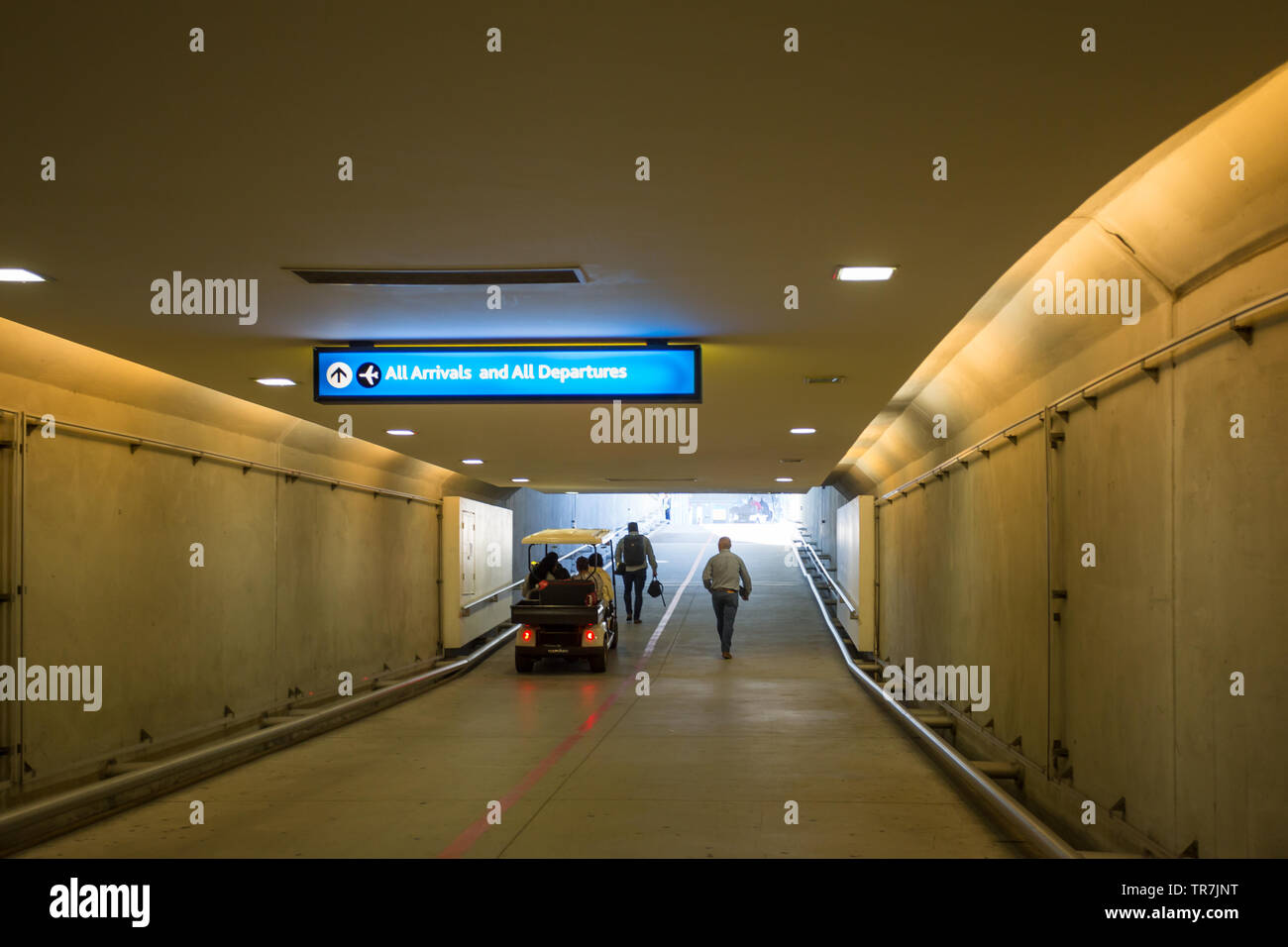 Persone di prendere una navetta e a piedi dal parcheggio auto sotterraneo attraverso un tunnel verso il terminale di edifici a Cape Town International Airport Foto Stock