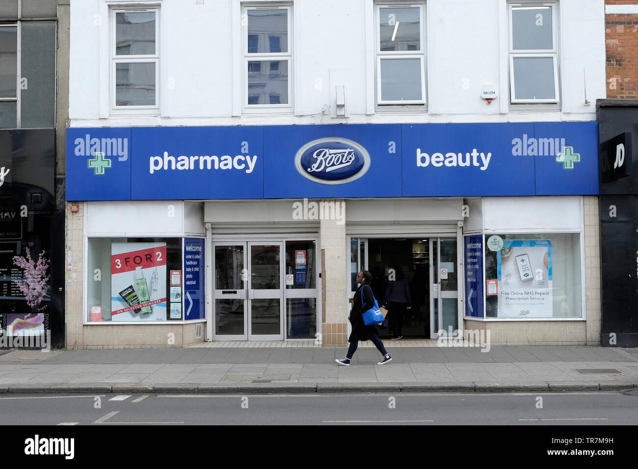 Una donna cammina passato scarponi a Kilburn High Road, Londra, Regno Unito Foto Stock