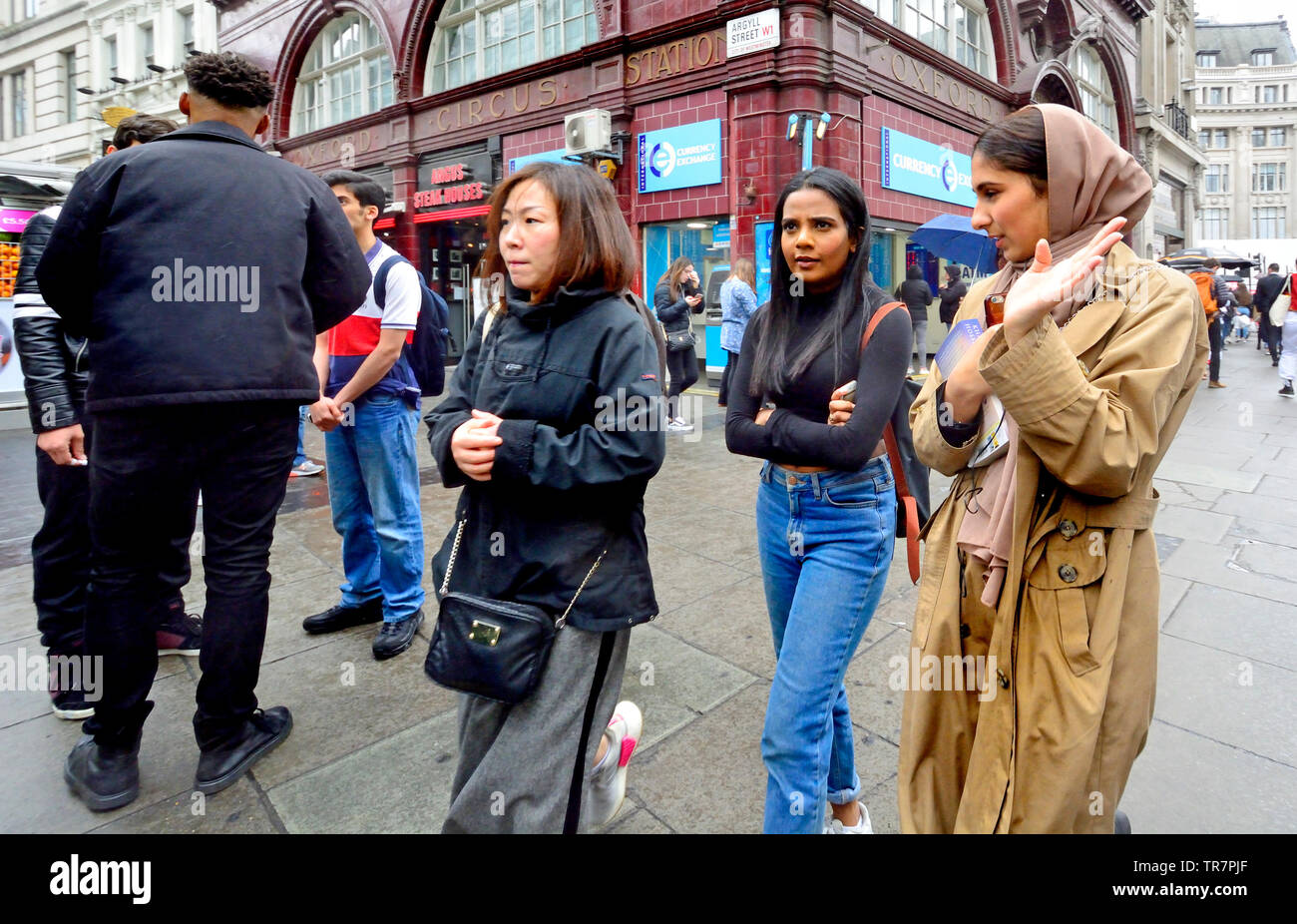 Londra, Inghilterra, Regno Unito. Persone di diverse minoranze etniche di shopping in Oxford Street in un giorno di pioggia Foto Stock