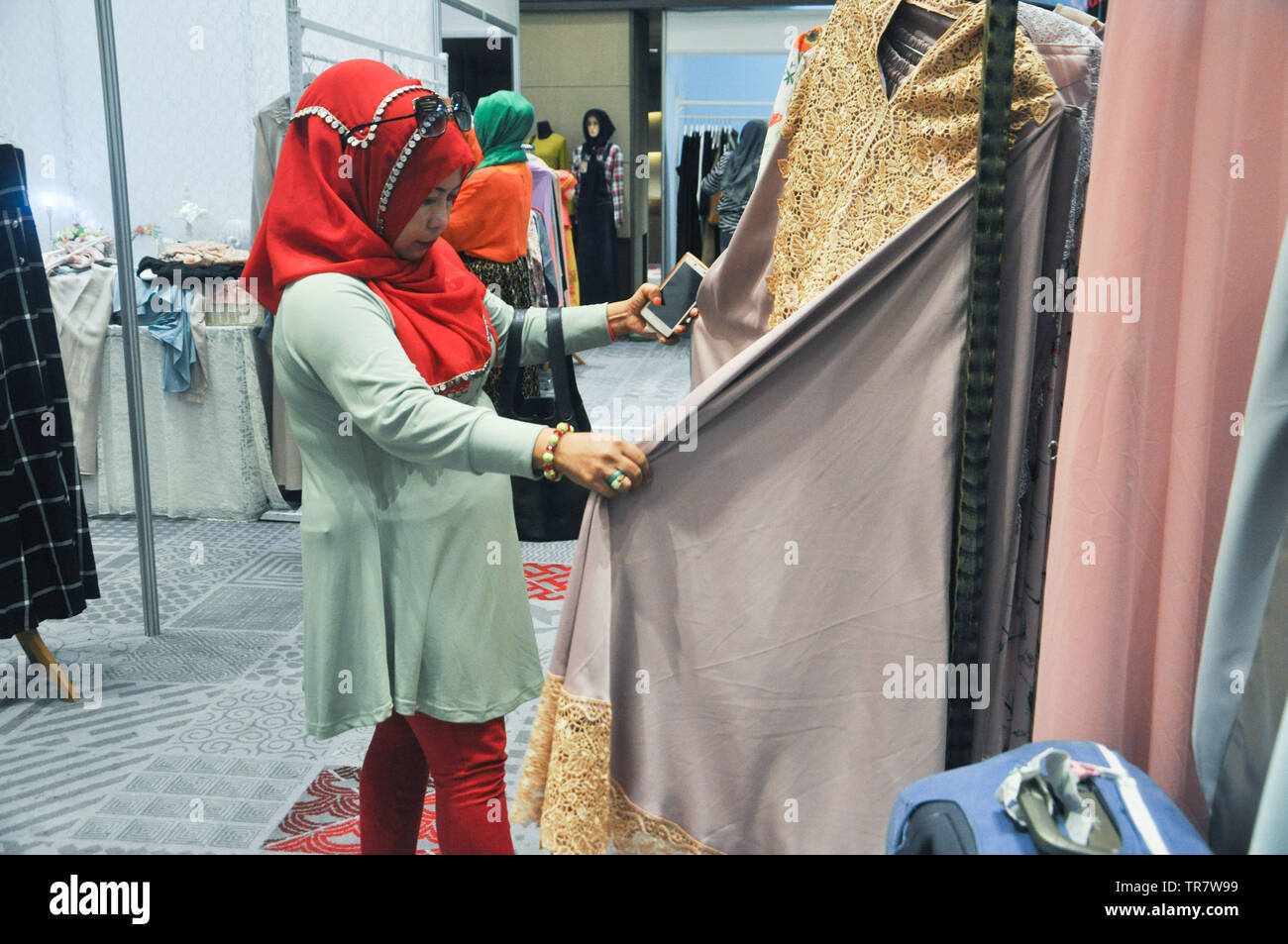Un musulmano indonesiano donna sceglie i vestiti a Indonesia musulmana Expo di moda. Musulmani industria moda cresce molto rapidamente in passato in Indonesia severa Foto Stock