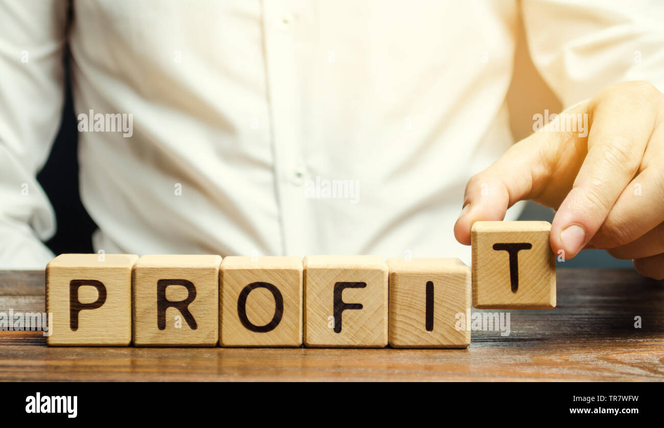 Imprenditore mette dei blocchi di legno con la parola profitto. Il risultato finanziario della società per un certo periodo di tempo. Reddito. Il ritorno sugli investimenti. P Foto Stock