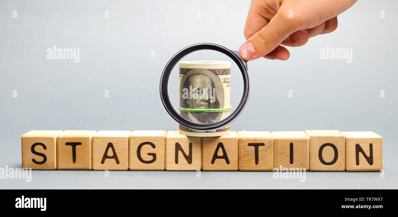 Blocchi di legno con la parola di stagnazione e di dollari. Prolungato periodo di lenta crescita economica, misurata in termini di crescita del PIL. Un elevato tasso di disoccupazione. Econ Foto Stock