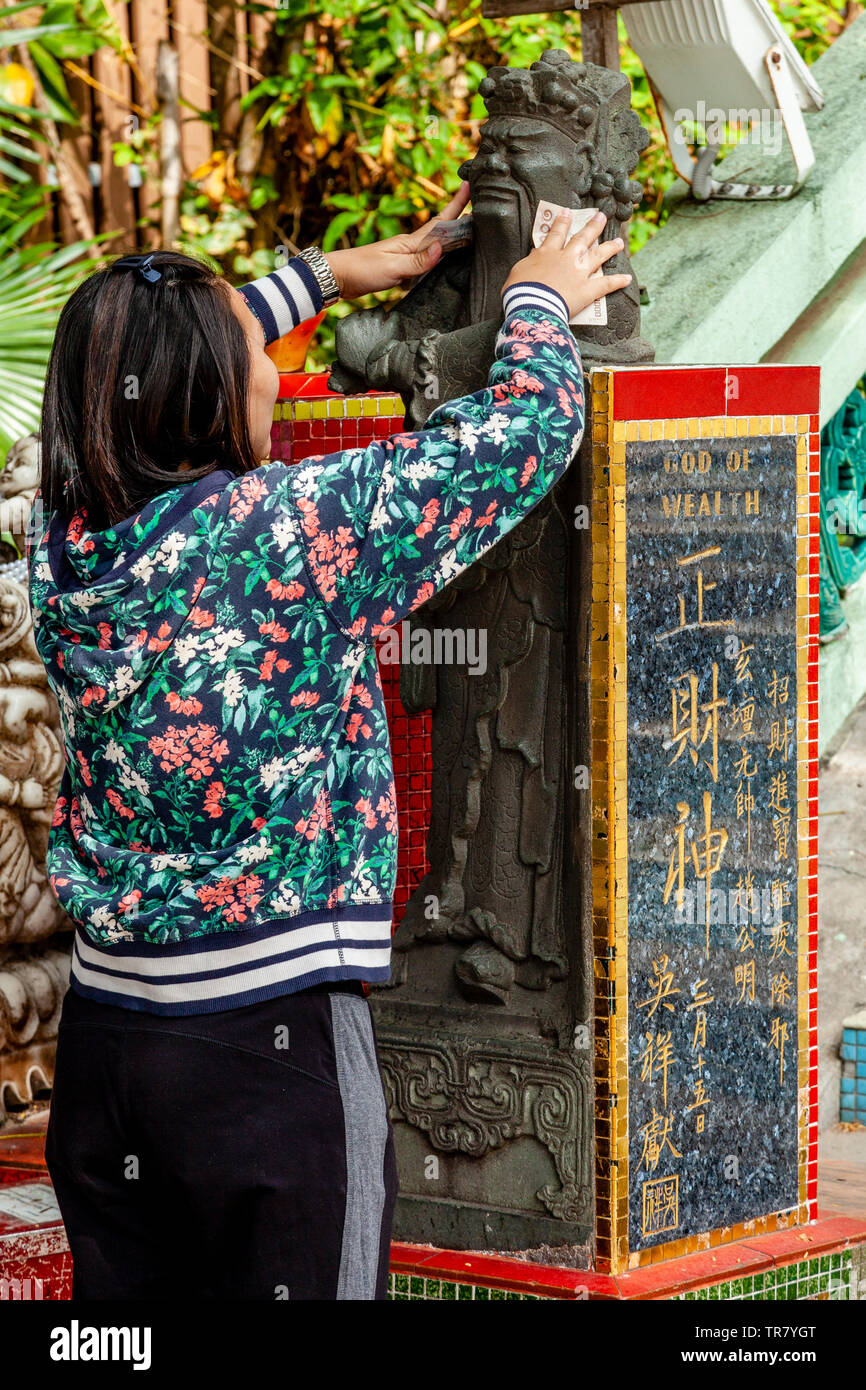 Turisti cinesi che sfregano contro il dio della ricchezza statua per portare la Buona fortuna, Kwun Yam Santuario, Repulse Bay, Hong Kong, Cina Foto Stock