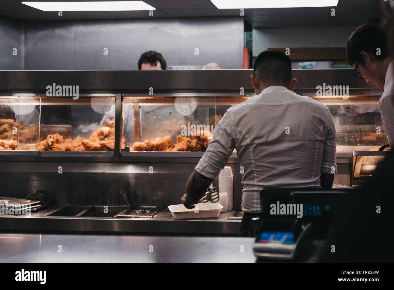 Pozzetti-next-il-Mare, Regno Unito - 20 Aprile 2019: il personale che serve pesce e patatine interno francese popolare di pesci e di chip shop in pozzetti-next-il-mare, una città di mare Foto Stock