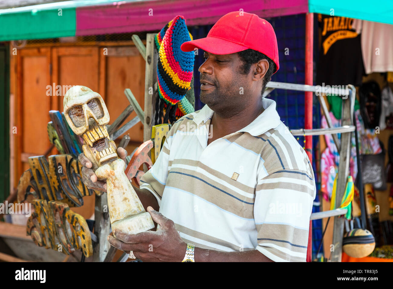 Stallholder locale a un tradizionale mercato di artigianato di trattenimento di un cranio ornamentali che ha scolpito in legno, artigianato, Ocho Rios, in Giamaica, Caraibi Foto Stock