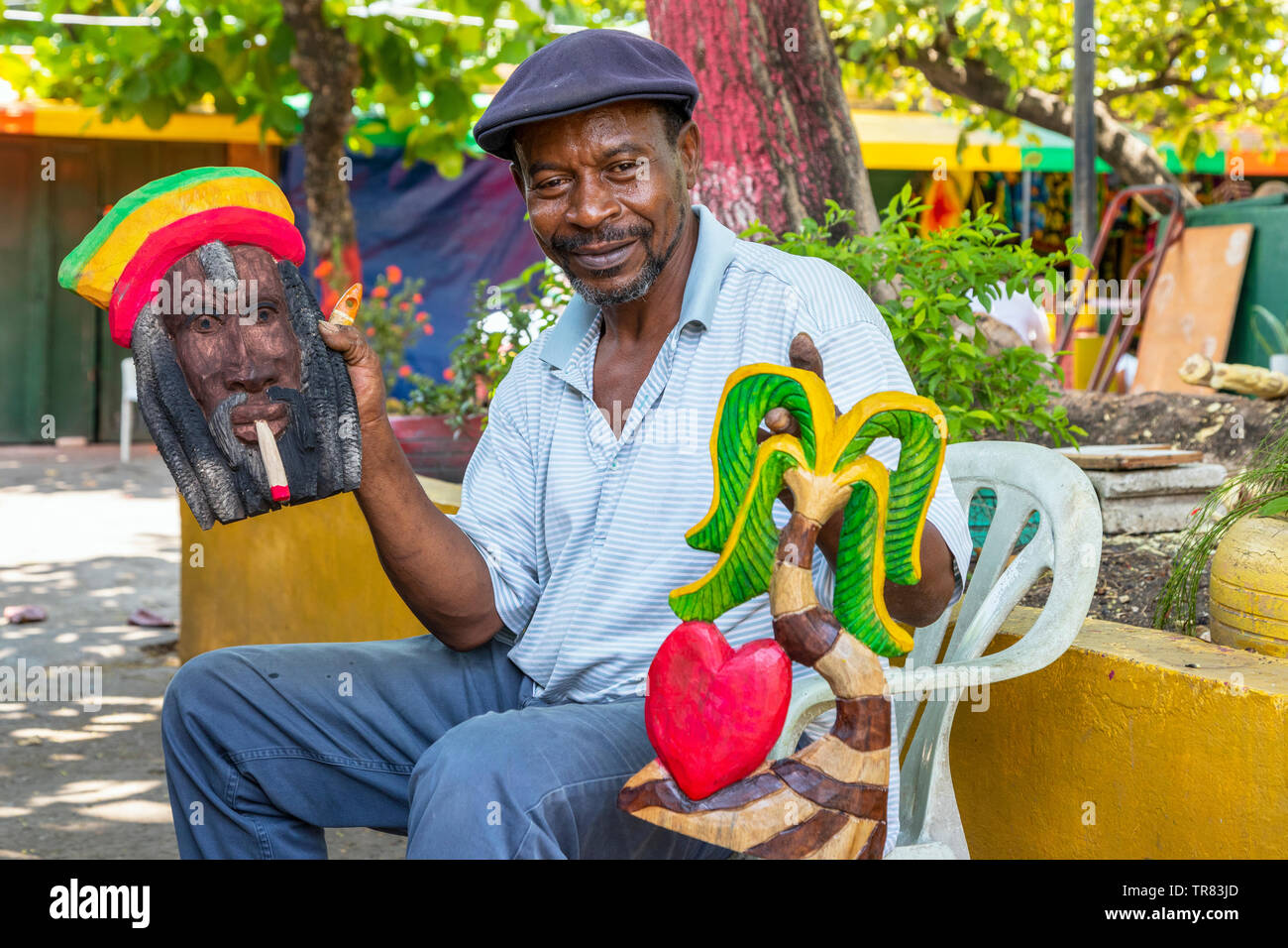 Negoziante locale tenendo un sculture in legno che egli ha fatto per vendere ai turisti presso il locale mercato artigianale, Ocho Rios, in Giamaica, Caraibi Foto Stock
