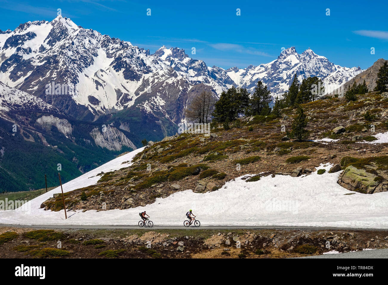 Due ciclisti e appassionati di mountain bike, sul Col du Granon, Briançon, Ecrins, Francia, con montagne innevate Foto Stock