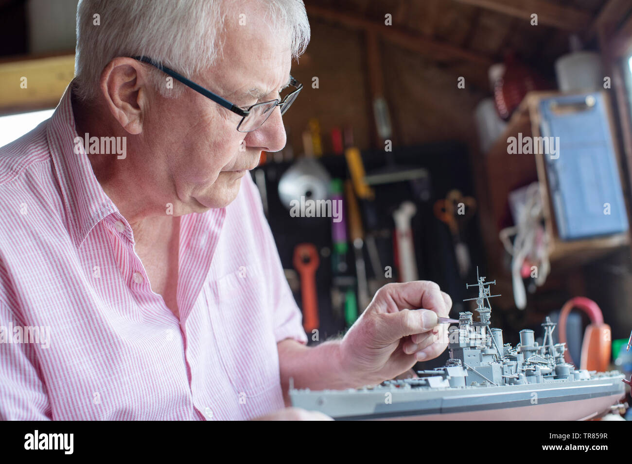 Senior uomo che lavora sul Modello di nave in un capannone a casa Foto Stock