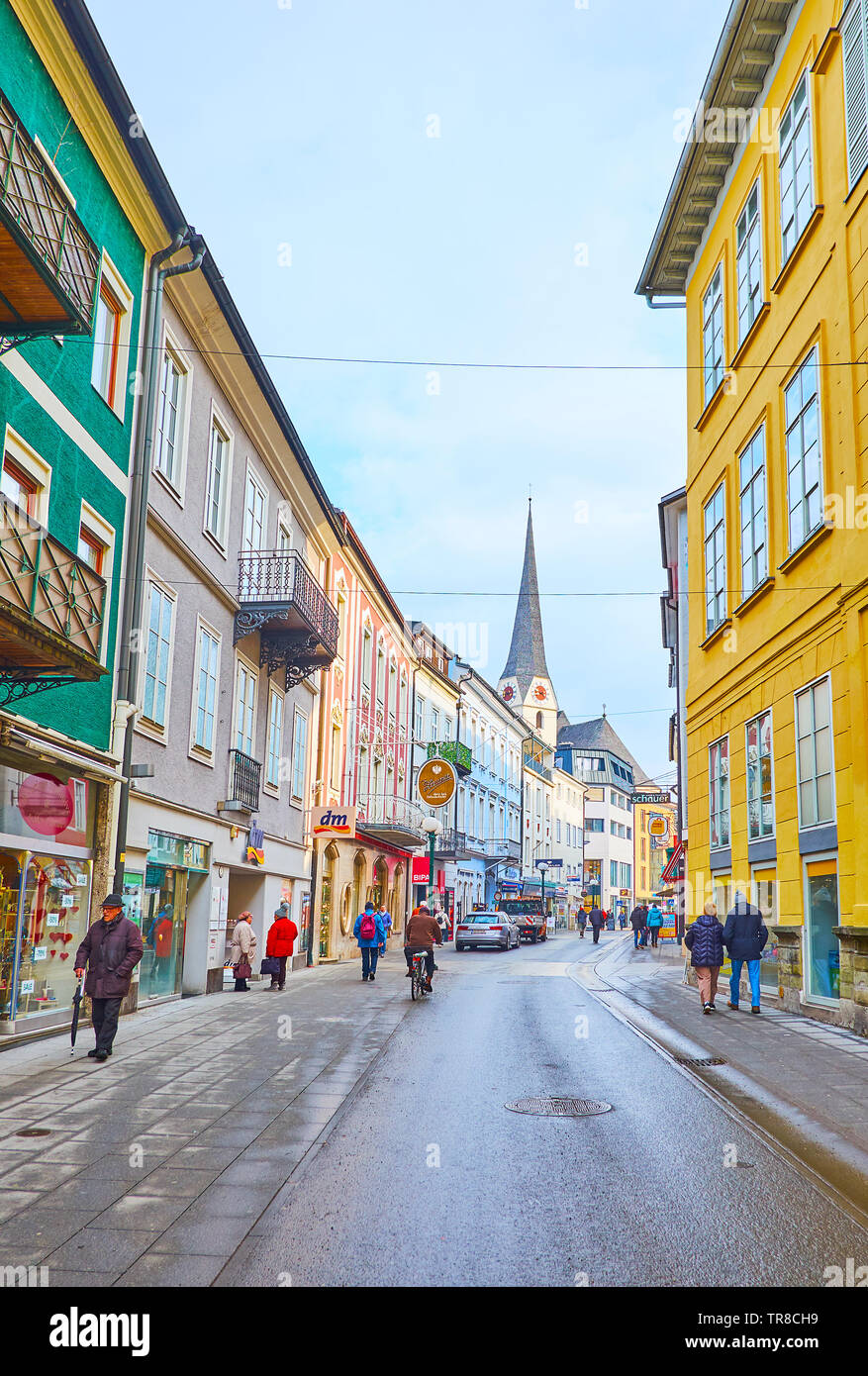 BAD Ischl Austria - 20 febbraio 2019: Pfarrgasse storica via commerciale con denso di edifici colorati e alto campanile della chiesa Parrocchiale su backg Foto Stock