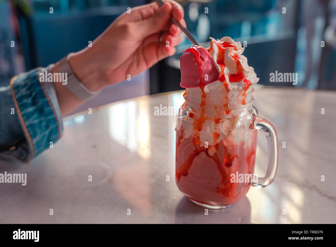 Testy gelato alla fragola. Boccale di cristallo con delicios gelato e fragola topping. Donna di mangiare gelato. Foto Stock