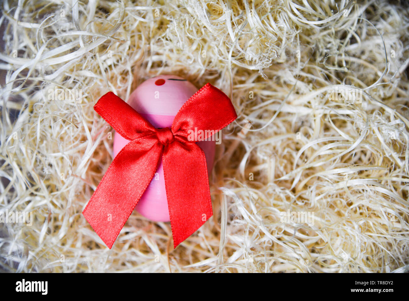 Rosa le uova di pasqua con il red ribbon bow nel nido su sfondo vista superiore Foto Stock