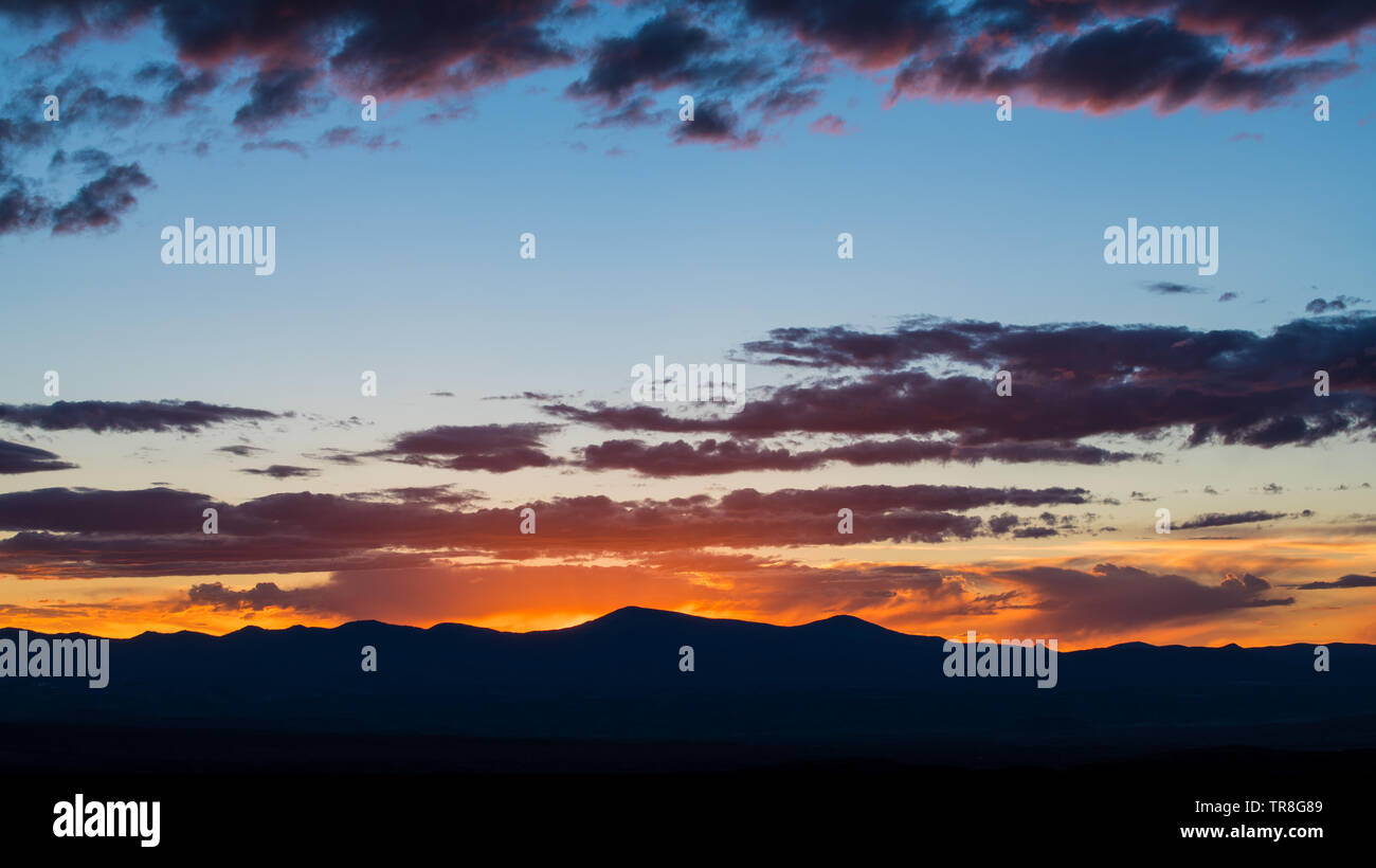 Silhouette al tramonto di una catena montuosa e si illumina una drammatica del cielo della sera con viola e rosa nuvole - Jemez montagne vicino a Santa Fe, New Mexico Foto Stock