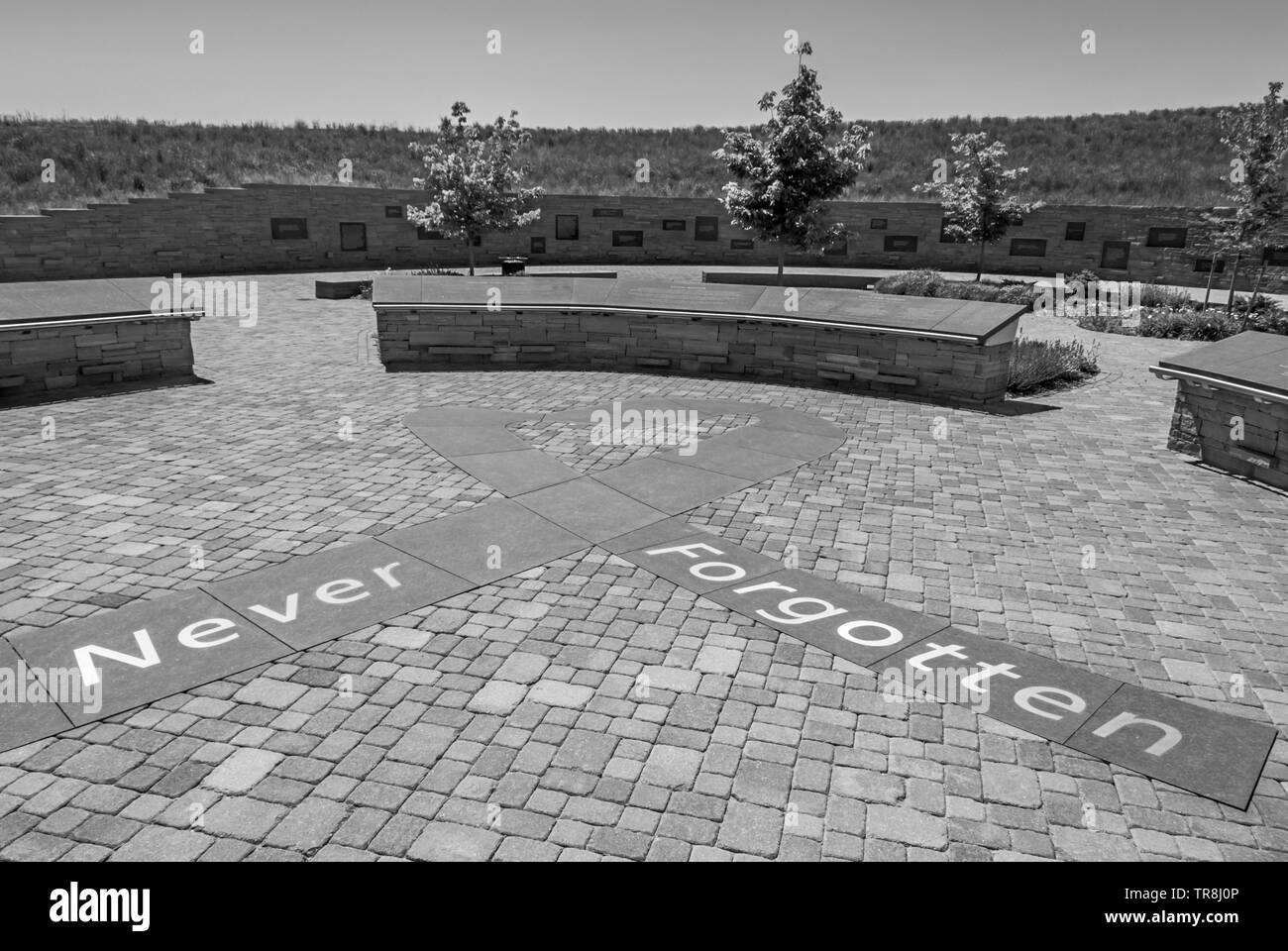 Ingresso alla Columbine High School Memorial che mostra le parole, "mai dimenticato" in primo piano e la visualizzazione di placche in distanza in bianco e nero. Foto Stock