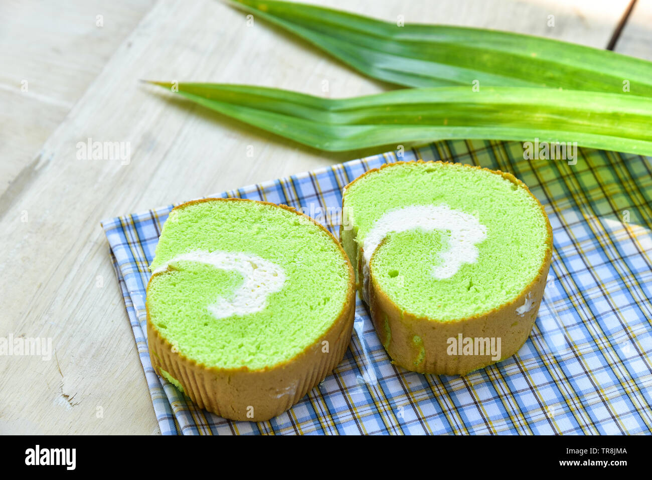 Pandan rotolo crema dolce pasticceria da forno su tessuto con panna fresca e Pandan leaf Foto Stock