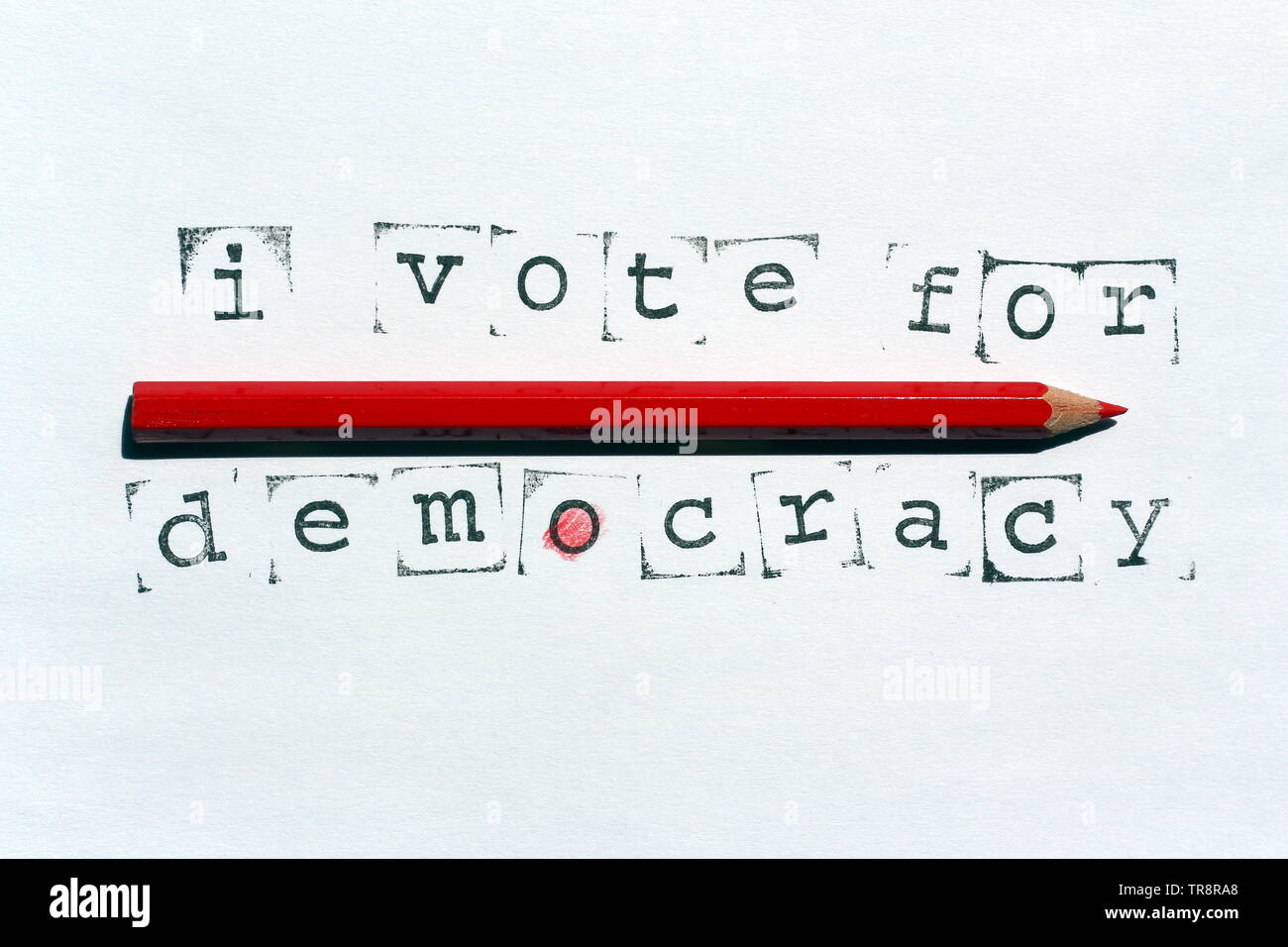 La democrazia, il concetto di immagine. Testo scritto con timbri e inchiostro su carta bianca e rossa matita in legno. Foto Stock