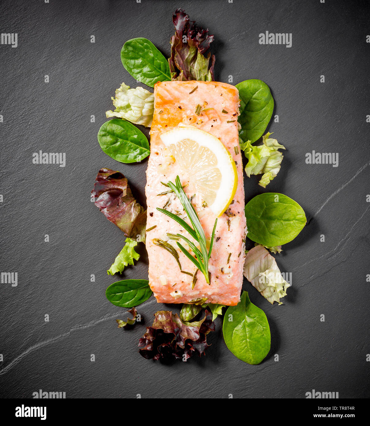 Filetto di salmone alla griglia con insalata su nero ardesia piastra, vista dall'alto Foto Stock