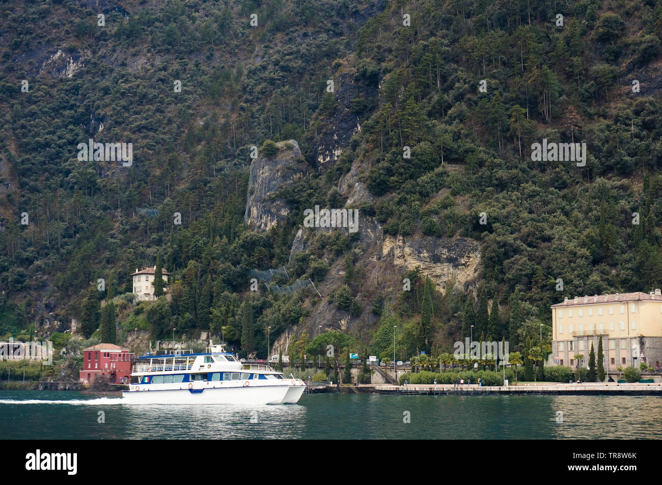 Riva di Garda, Italia - Marzo 2018: barca sul lago verde delle montagne sullo sfondo Foto Stock