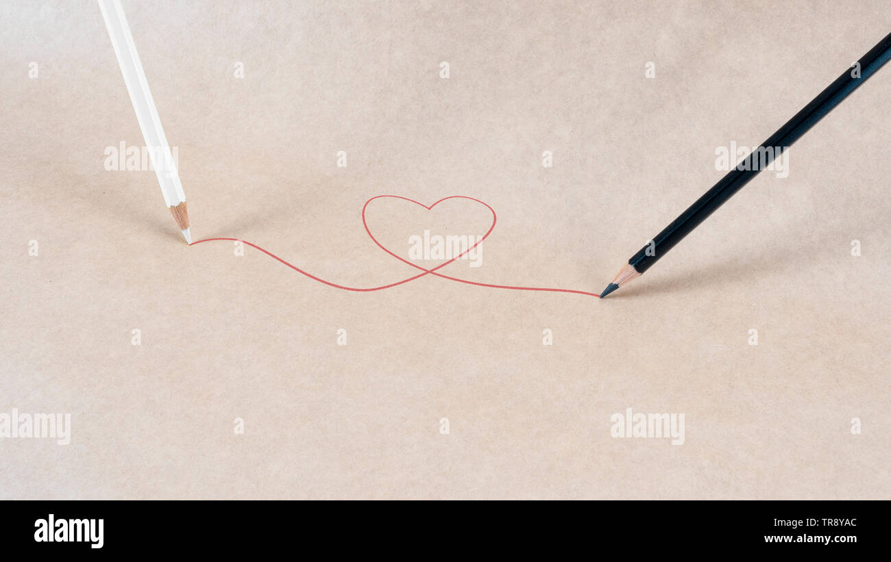 Interracial. Una matita bianca e nera di un disegno a matita di un cuore rosso. Foto Stock