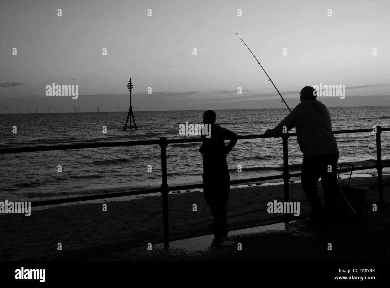 Nonno & nipote pesca al largo della parete del mare a Crosby beach Liverpool. Foto Stock