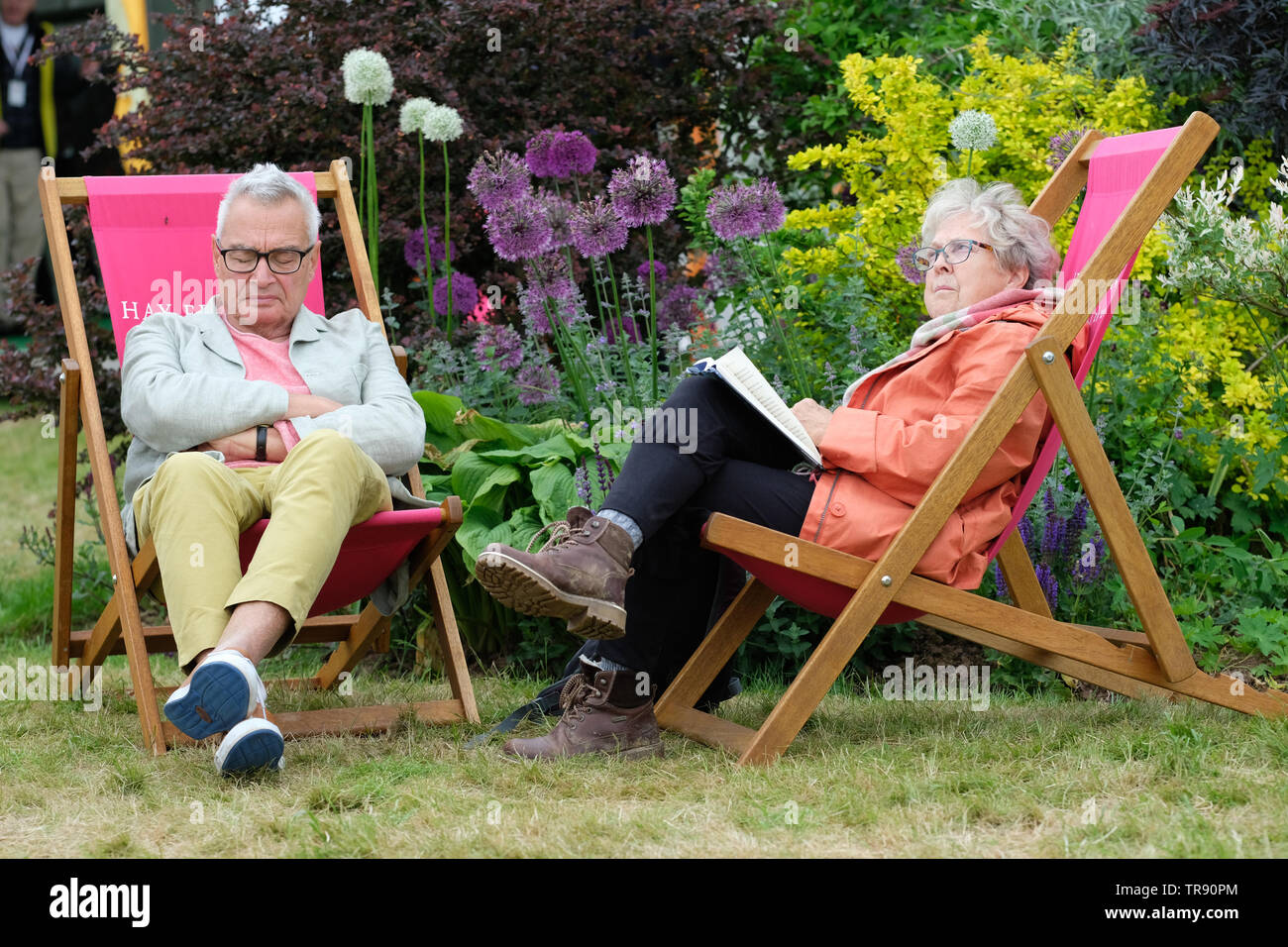 Festival di fieno, Hay on Wye, Powys, Wales, Regno Unito - Venerdì 31 Maggio 2019 - un visitatore getta un occhio sul meteo come due visitatori apprezzano la possibilità di sedersi e riposare nelle sedie a sdraio sul Festival di prati tra gli eventi. Foto Steven Maggio / Alamy Live News Foto Stock