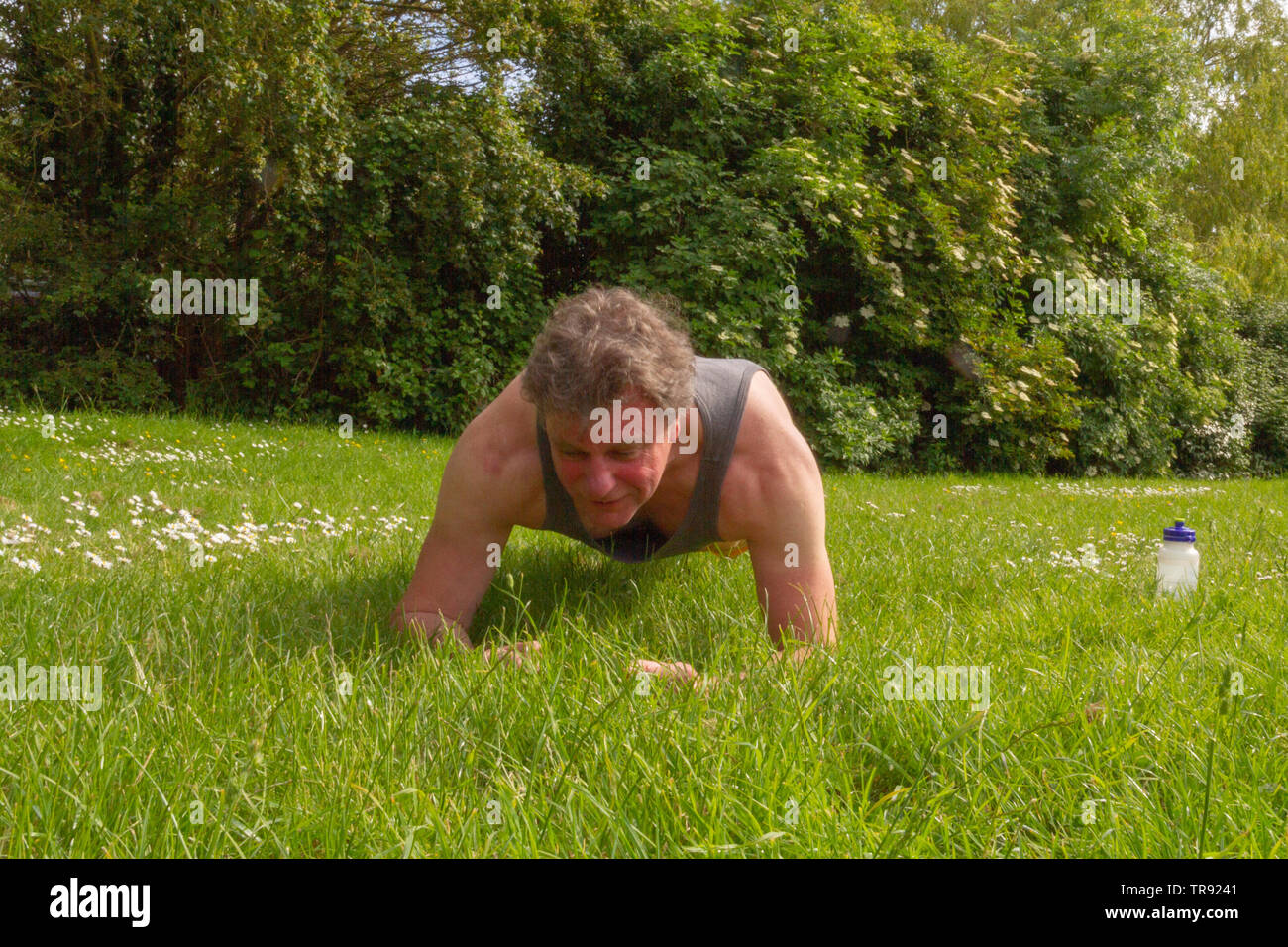 Baby Boomer eseguendo la "plank' esercizio all'aperto in un parco. Un sano stile di vita all'aperto concetto. Foto Stock