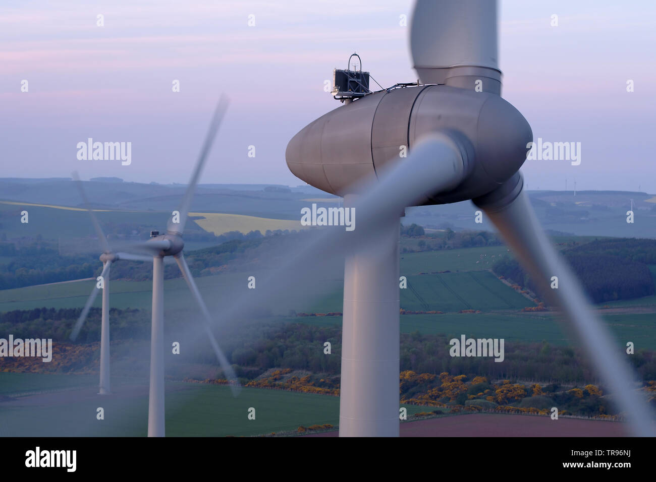 Una veduta aerea di tre turbine eoliche passando come il sole comincia a impostare, Aberdeenshire, Scotland, Regno Unito Foto Stock