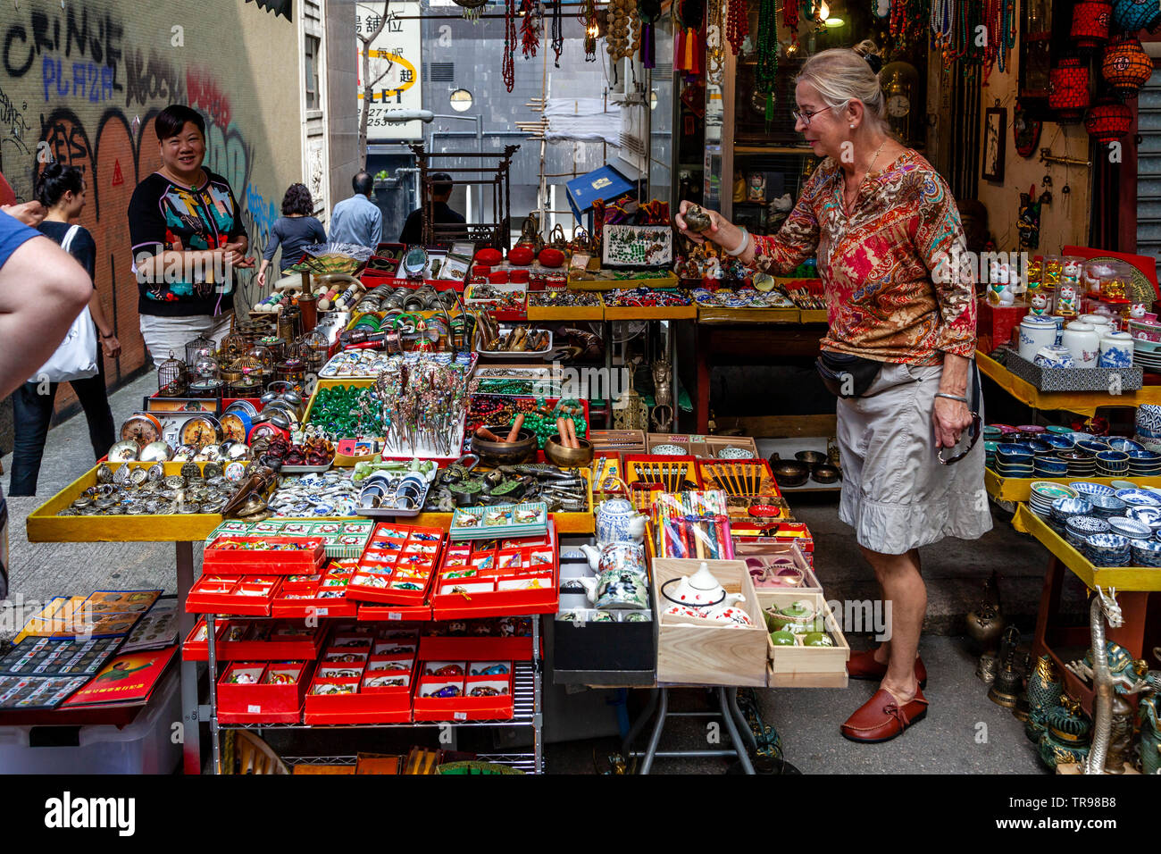 Una donna europea navigando in un Bric-a-Brac stallo, Tung Street, Hong Kong, Cina Foto Stock