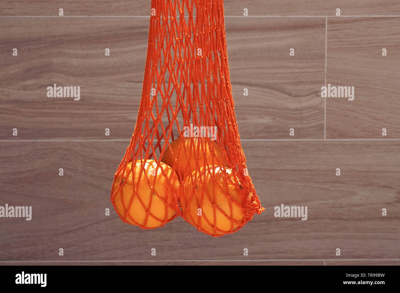 Stringa di fatti a mano borsa con tre arance Foto Stock