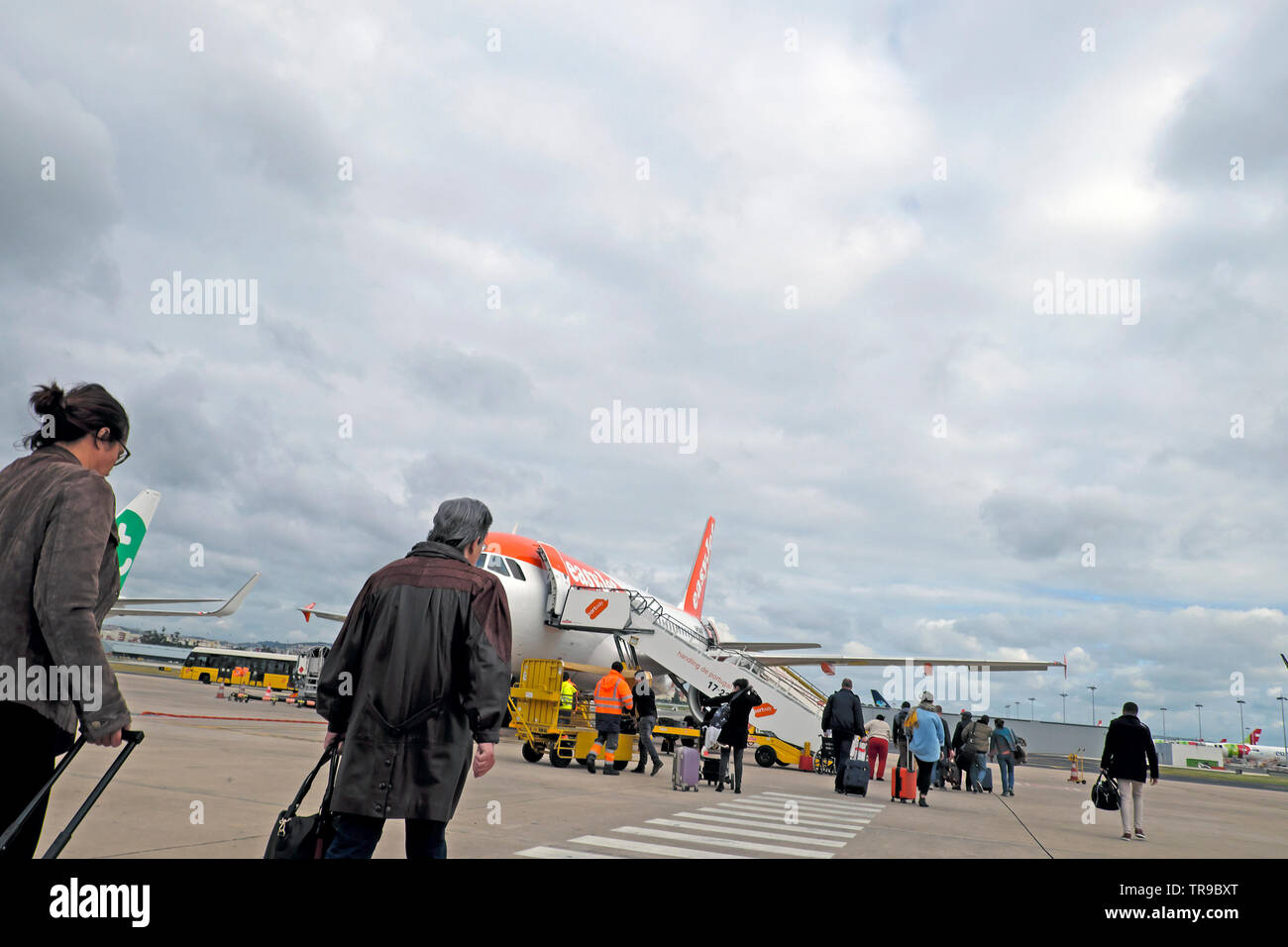 I passeggeri con bagaglio a mano all'aeroporto di Lisbona attraversano l'asfalto per salire a bordo di un facile aereo jet per volare a Londra Inghilterra Regno Unito 2019 KATHY DEWITT Foto Stock
