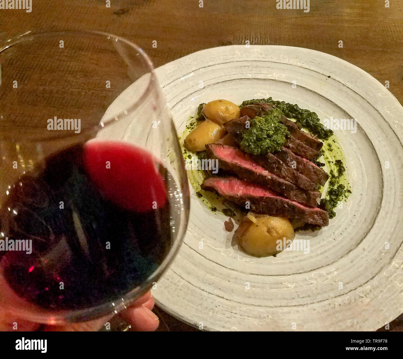 Grigliate di ferro piatto di bistecca con patate fingerling e un bicchiere di vino rosso. Foto Stock