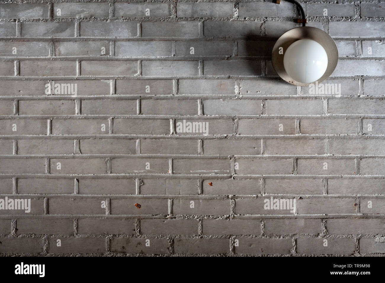 Vecchia lampada elettrica nel garage un muro di mattoni Foto Stock