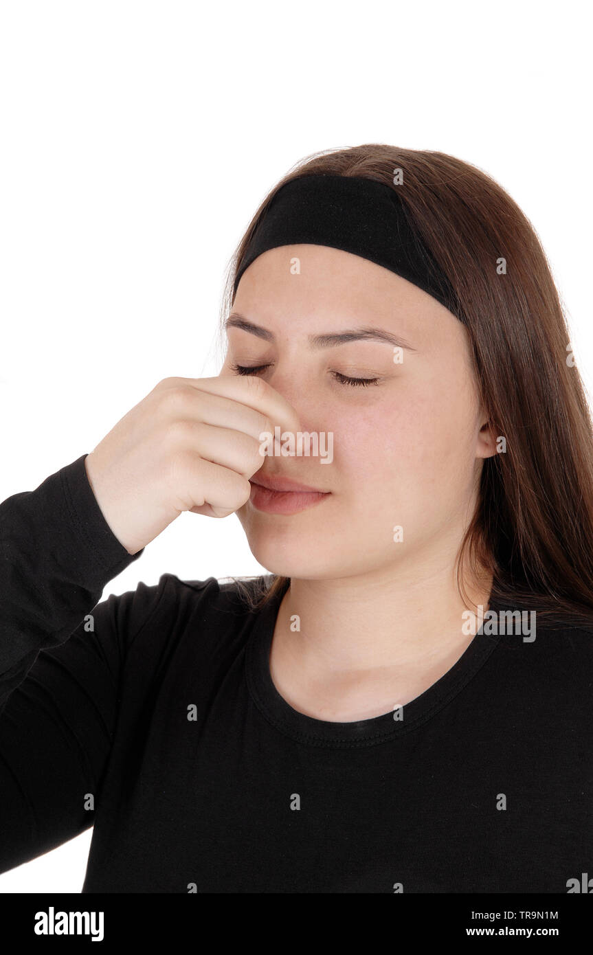 Un disgustato adolescente ragazza con il suo naso chiuso per il cattivo odore, con gli occhi chiusi l'odore è così male, isolato per sfondo bianco Foto Stock