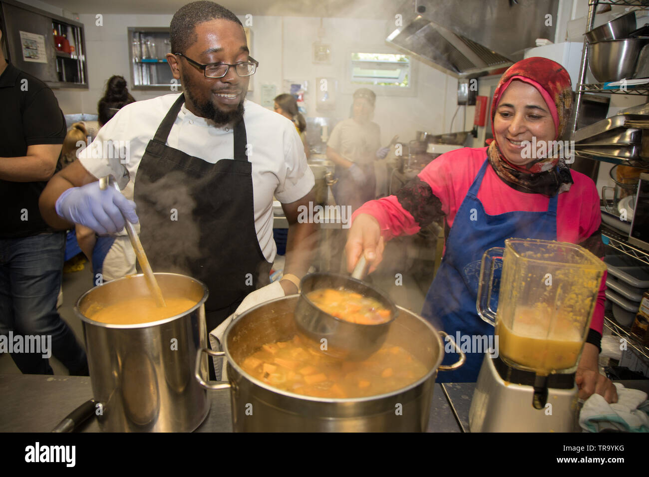 Volontari di una comunità cucina preparare un pasto per diners nel bisogno. Foto Stock