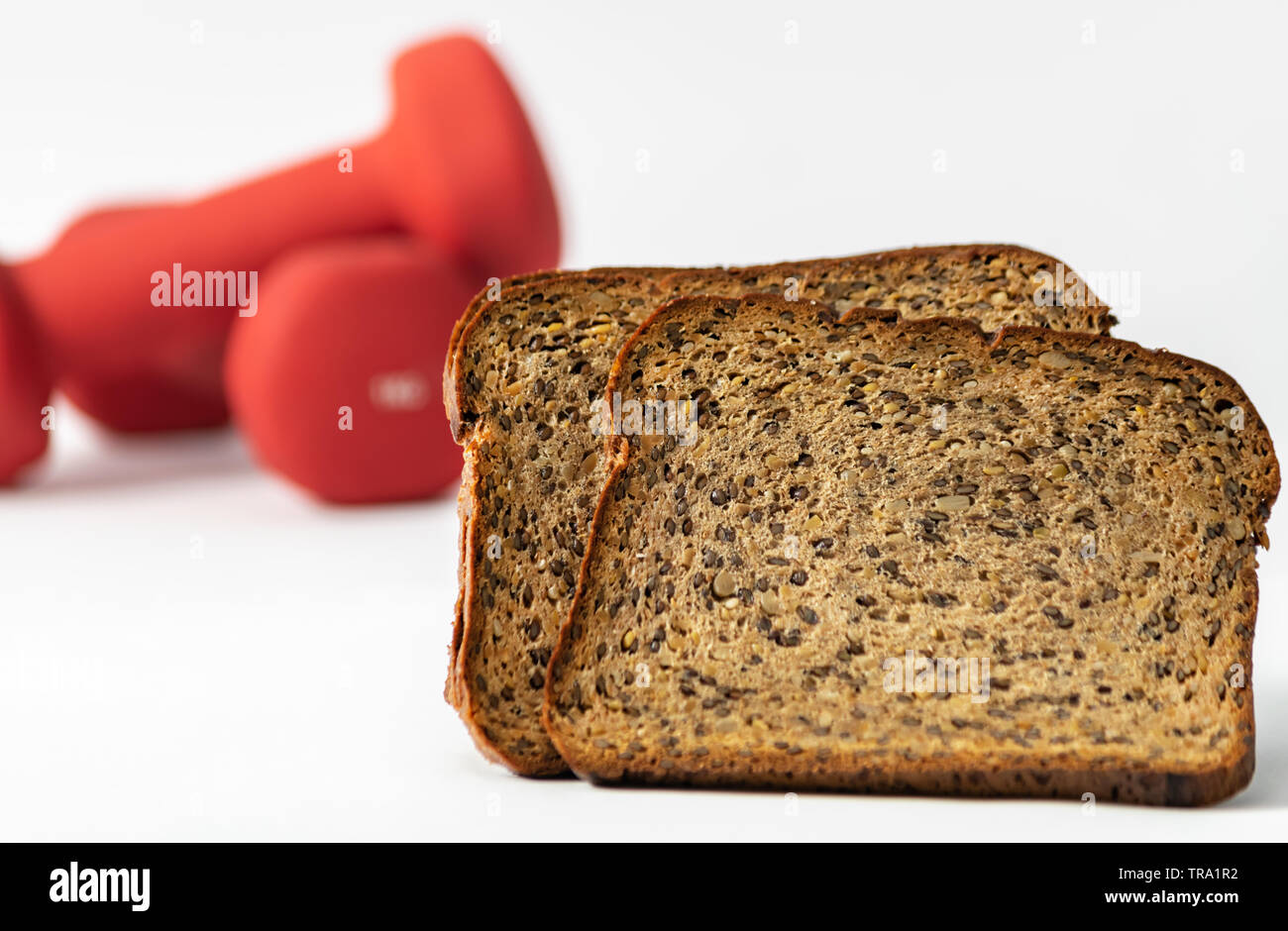 Proteina di fitness pane e non focalizzato manubri rosso su sfondo. Stile di vita Helthy sport concetto. Foto Stock