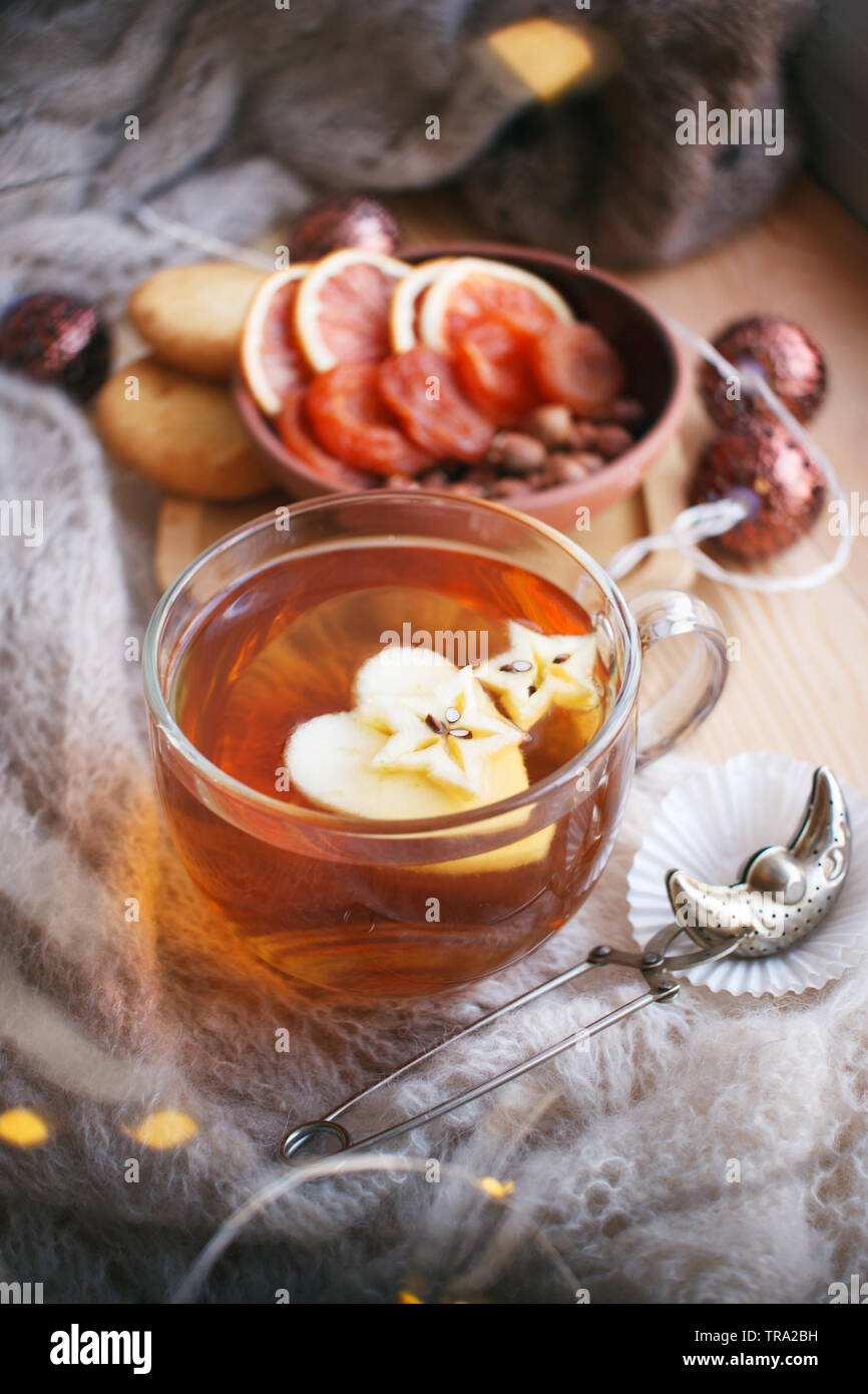 Tazza di tè, libro, caldo cuscino, ghirlanda luminosa in legno sul davanzale, Moody stagionale ancora in vita. Toni caldi, verticale, spazio di copia Foto Stock