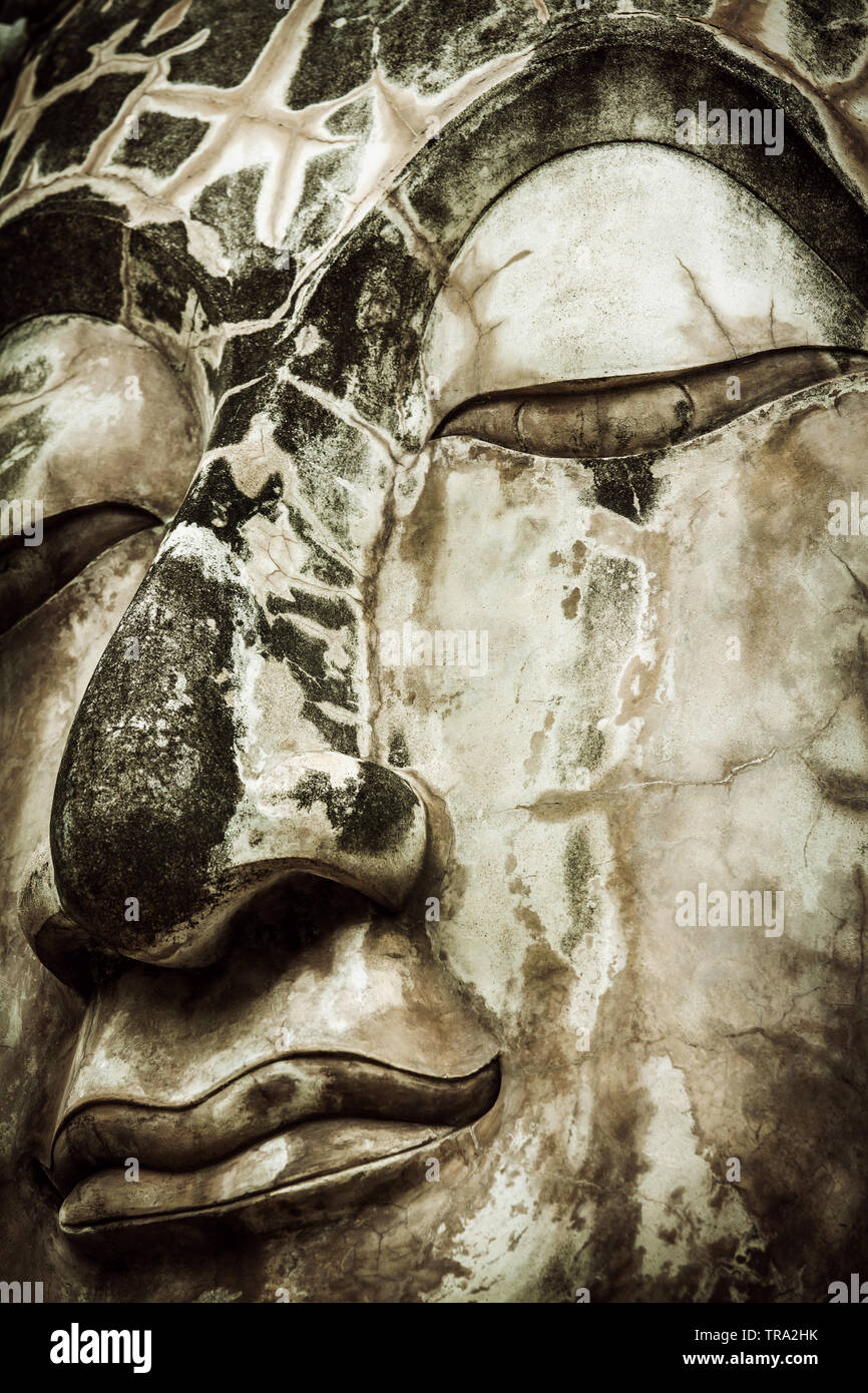 Abbandonata o fatiscente faccia del Buddha con gli occhi chiusi nella contemplazione. Close-up e dettagliata immagine verticale di un Big Buddha faccia. Un immagine astratta Foto Stock