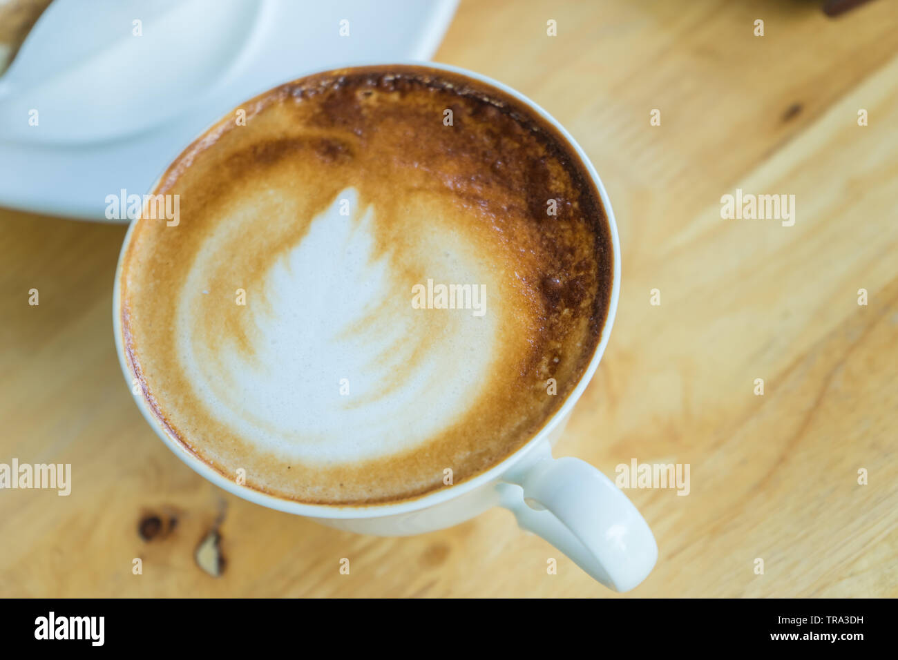 Caffè caldo in ritardo in vetro bianco sul tavolo di legno, Foto Stock