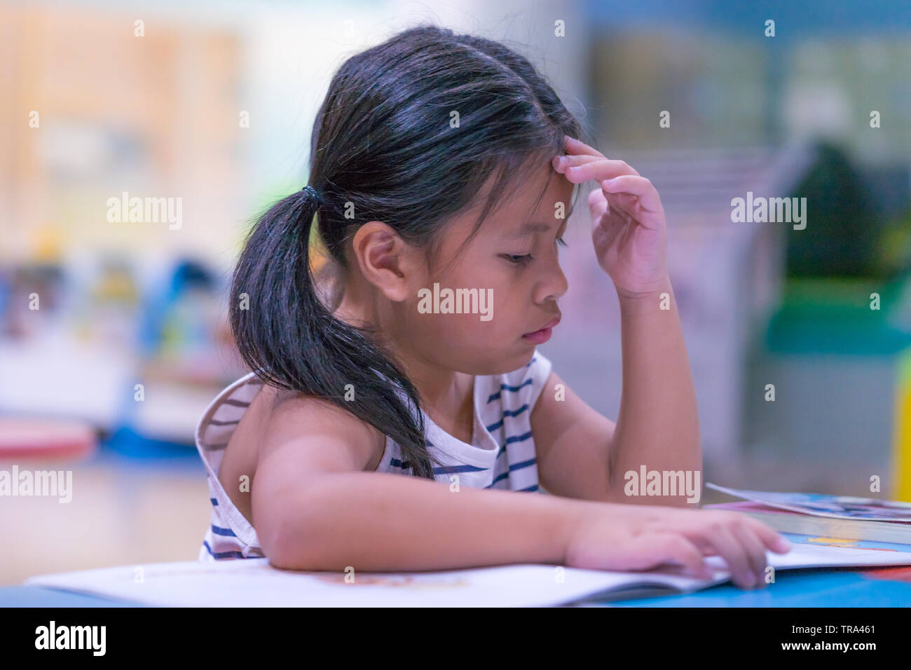Asian carino bambina imparare un libro in sala biblioteca, Foto Stock