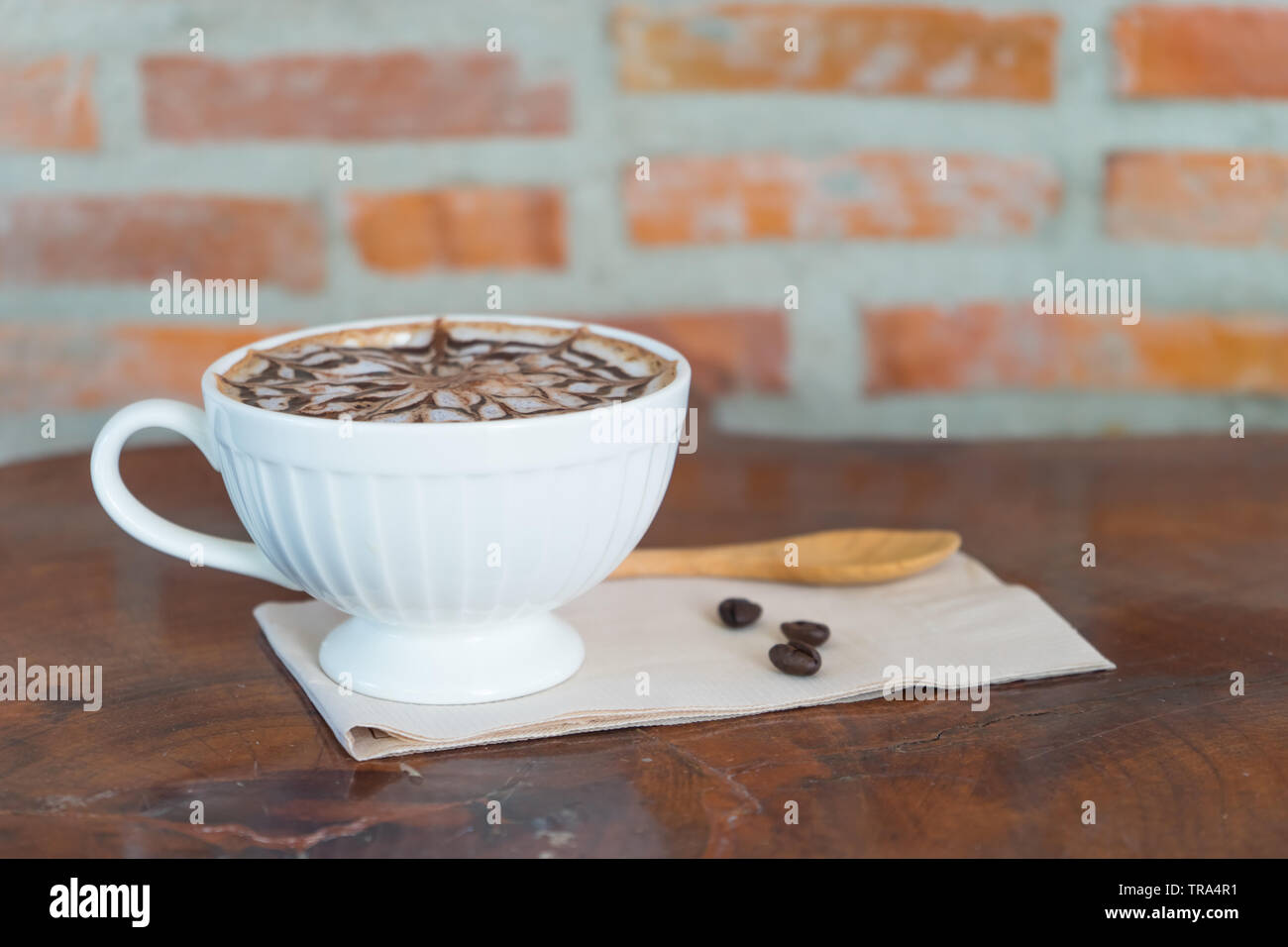 Caffè caldo in ritardo in vetro bianco sul tavolo di legno, offuscata caffè crudo, Foto Stock