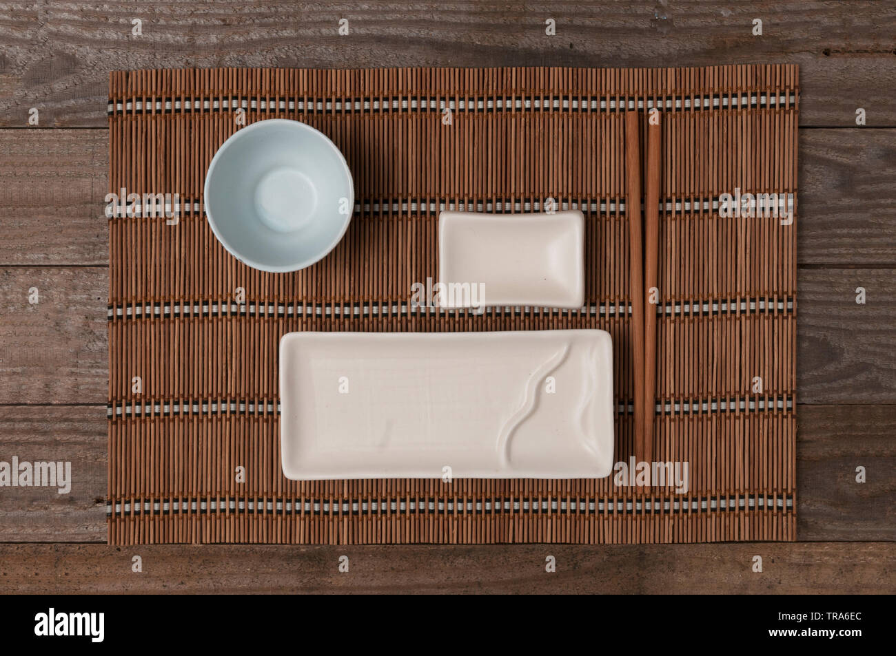 Piastra in ceramica per il sushi e cucina giapponese con baguette e ciotola per la salsa di soia sul tappetino di bambù vista superiore Foto Stock