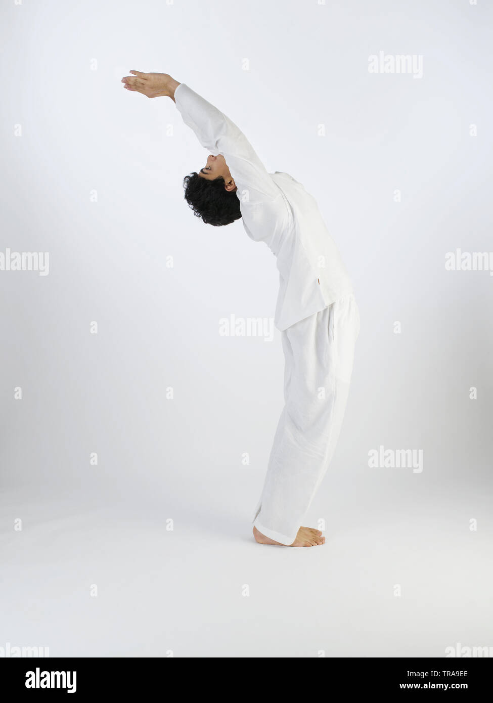 Ritratto di un giovane ragazzo di eseguire il surya namaskar pongono #2 chiamato bracci sollevati pongono (Hasta Uttanasana) Foto Stock