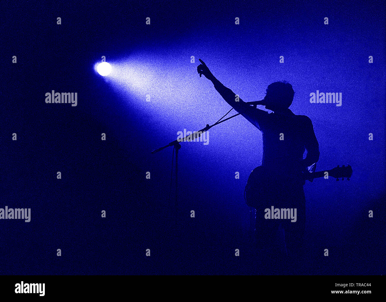 Incredibile la silhouette di un professionista chitarrista cantante bandleader sul palco con il suo braccio ringraziando la folla nel microfono per una splendida serata Foto Stock
