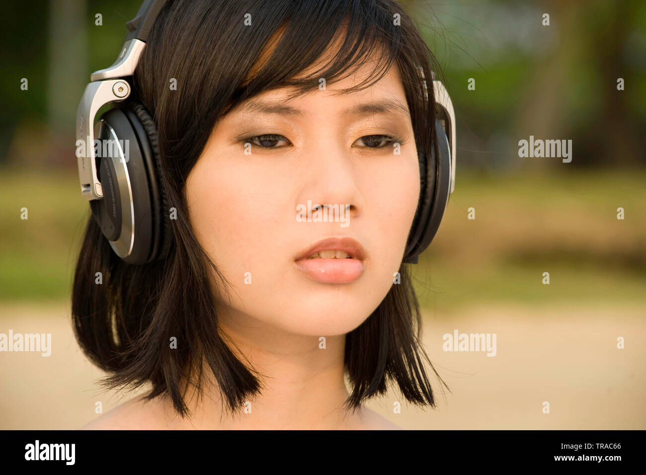 Ritratto di un moderno fresco giovane donna asiatica indossare cuffie di grande ascolto di musica Foto Stock
