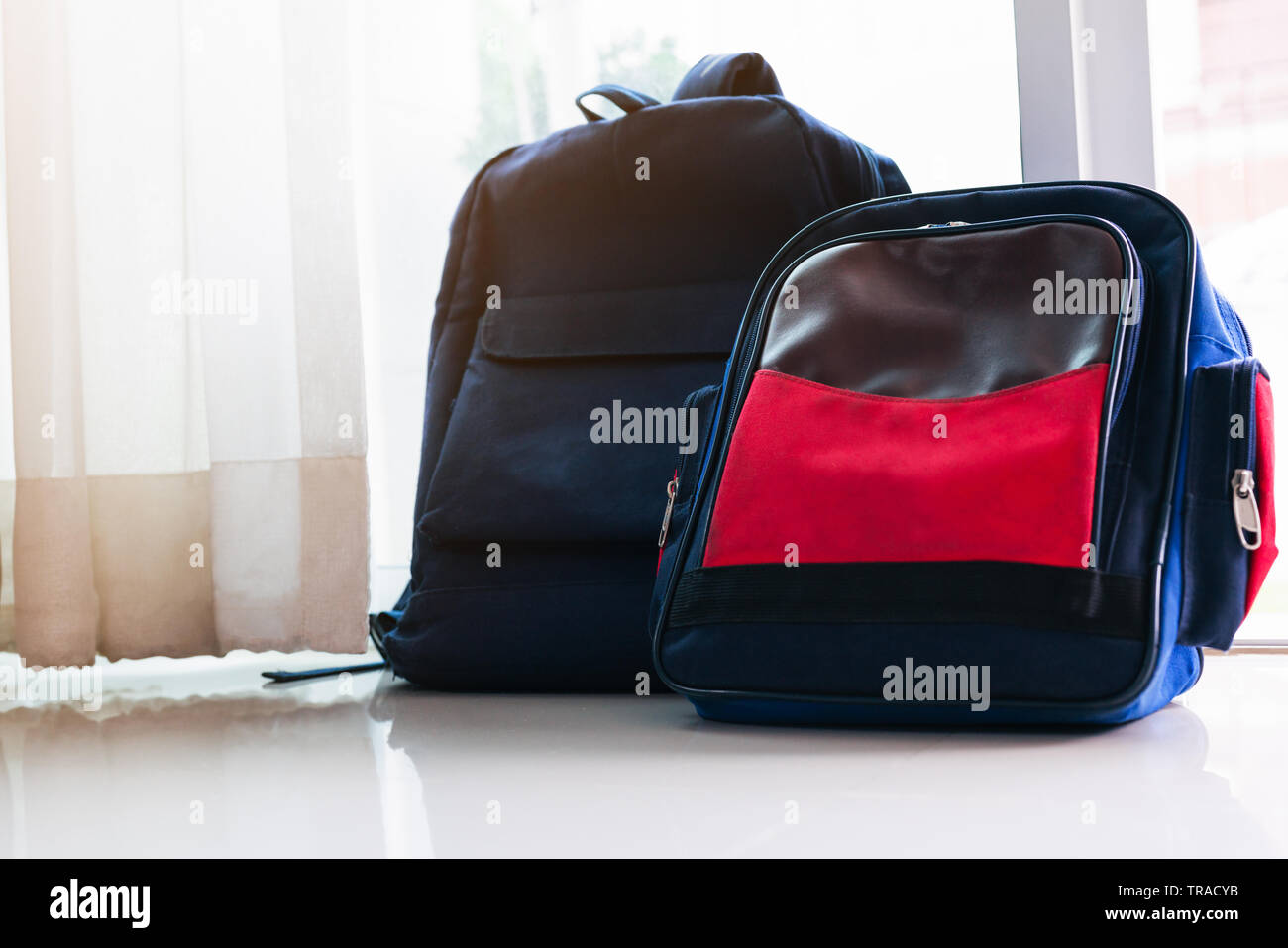 Si torna a scuola concetto. Zaino Blu si appoggia sulla porta di vetro per due bambini Foto Stock