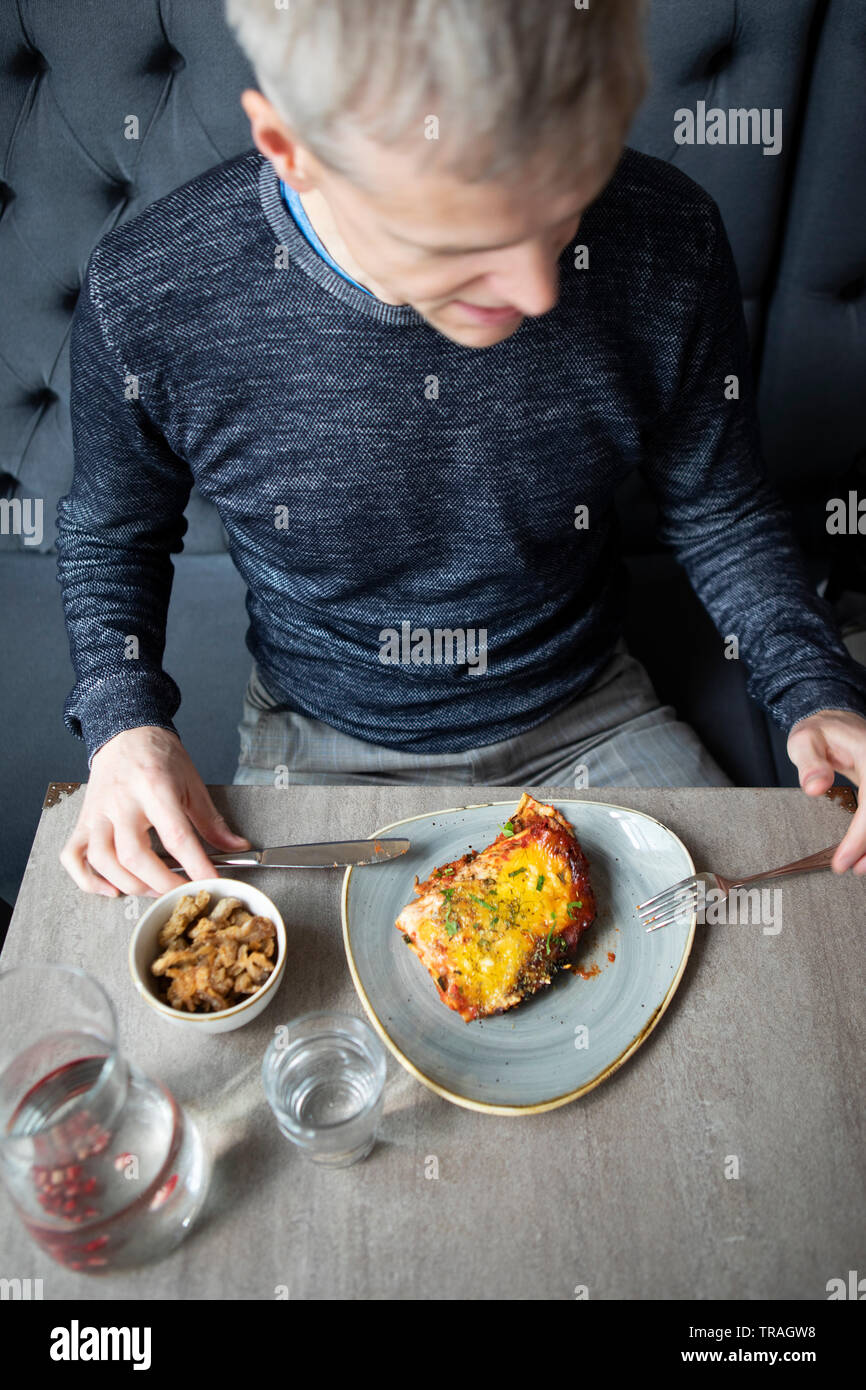 Mangiare in un ristorante, l'uomo mangiare lasagne, uomo avente lunsh Foto Stock