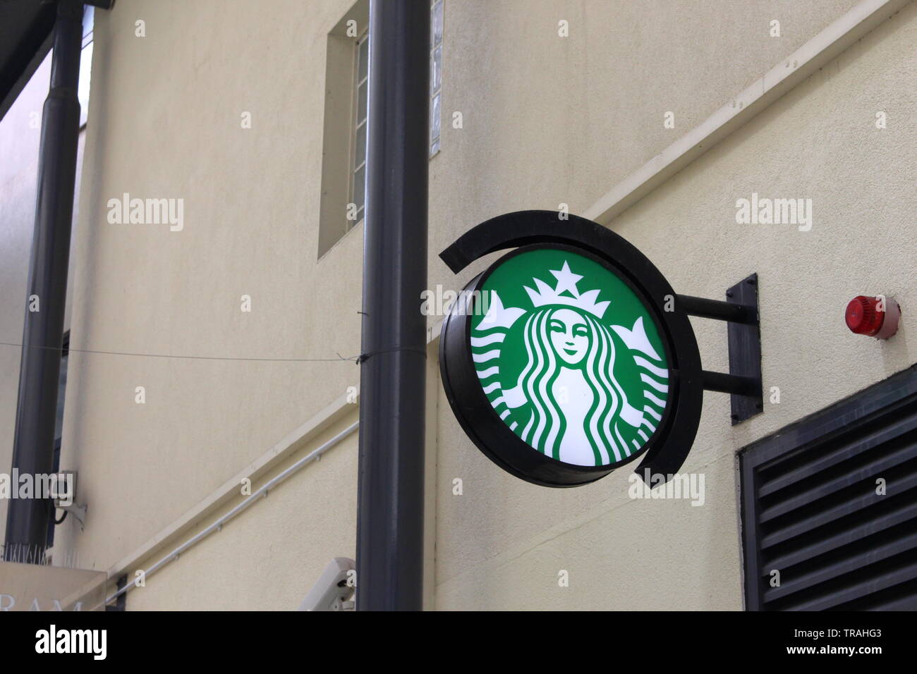 Una fotografia di un segno di Starbucks, all'aperto, attaccato ad un edificio semplice facciata. Industriali, segno commerciale Foto Stock