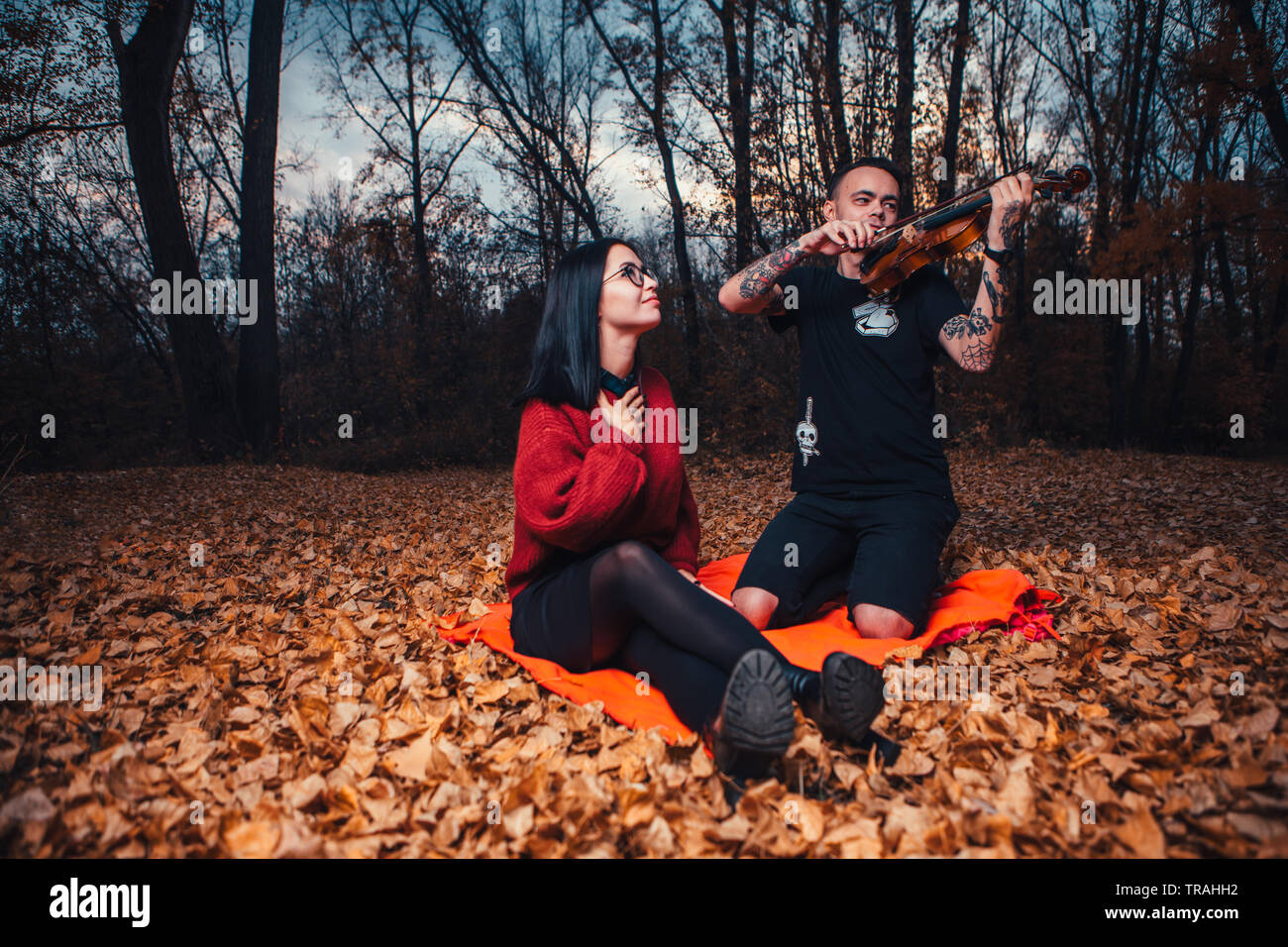 Il giovane e la giovane donna sono seduti su un plaid in una foresta d'autunno. Foto Stock