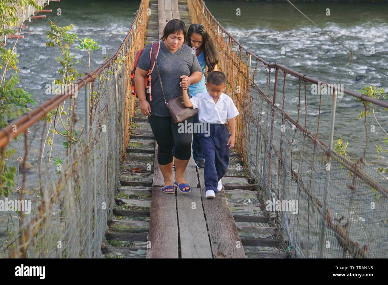 Kiulu Sabah Malaysia - Jan 2, 2019 : Unidentified Madre che accompagna il suo figlio camminando sul ponte di sospensione passerella per frequentare la prima giornata di sessione di scuola. Foto Stock