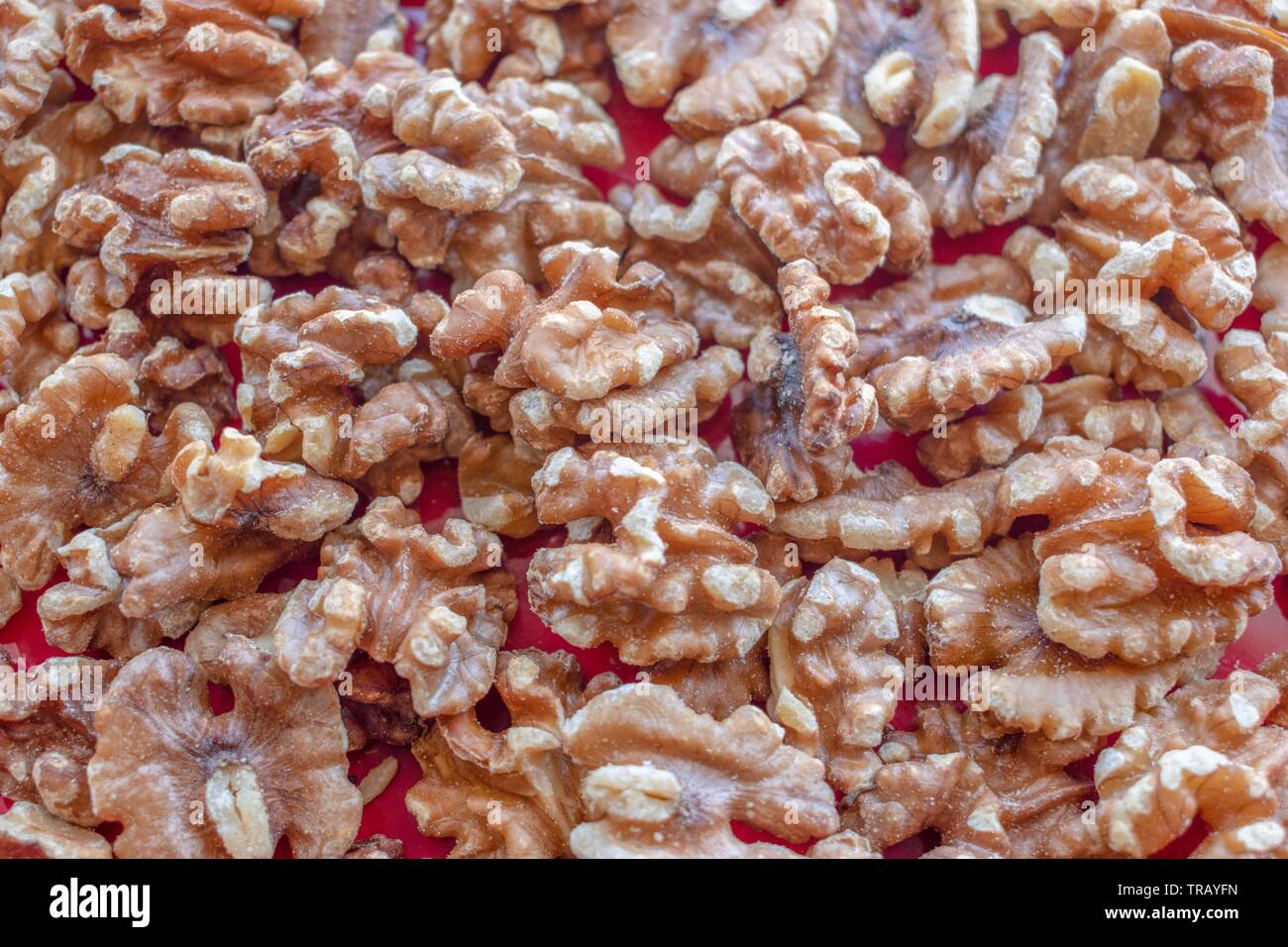 Tettuccio di vista ravvicinata di un mazzetto di noci senza i loro gusci su uno sfondo rosso Foto Stock
